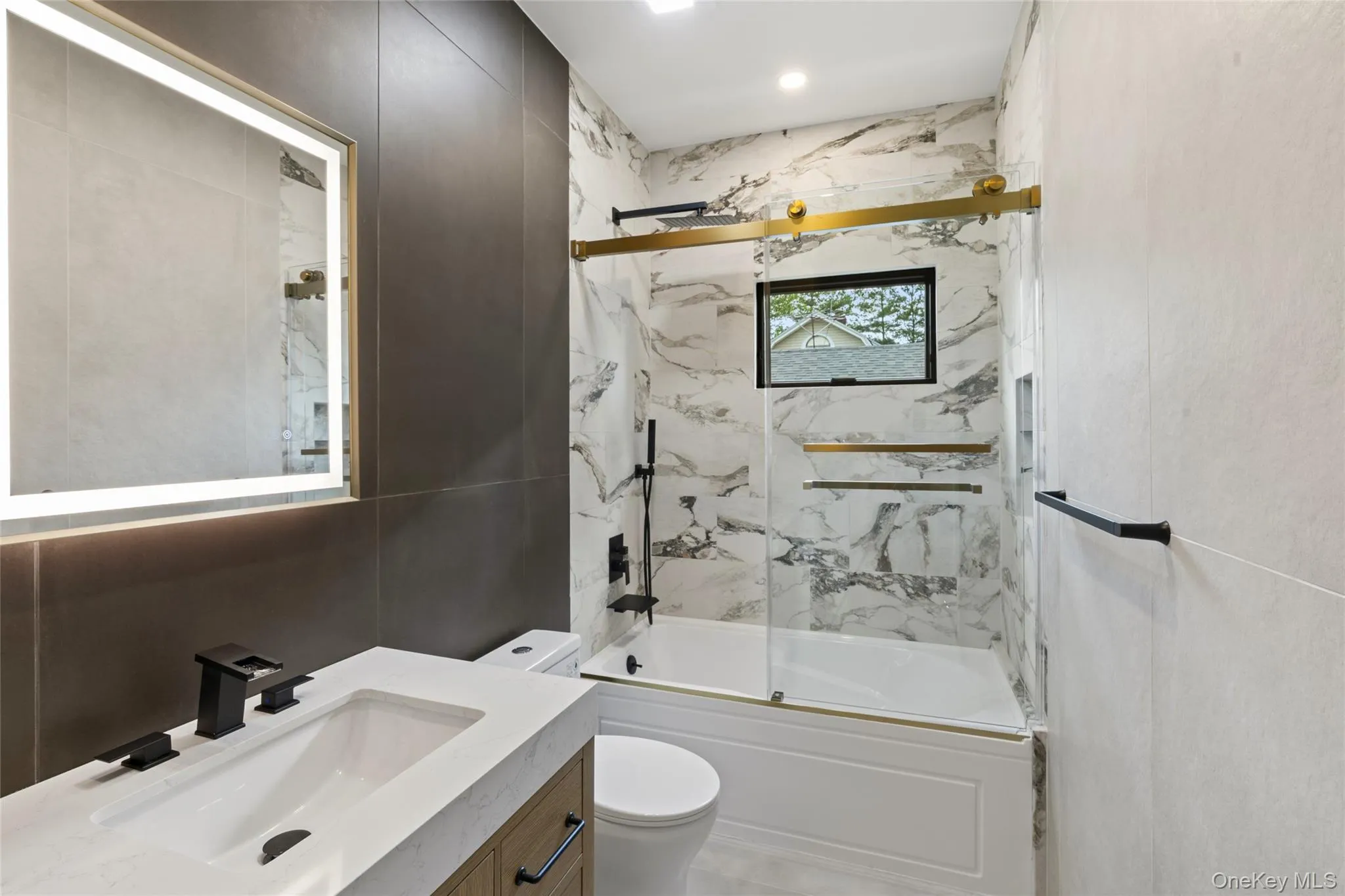 Contemporary bathroom featuring a vanity with integrated sink, matte black fixtures, and an illuminated mirror Contemporary bathroom featuring a vanity with integrated sink, matte black fixtures, and an illuminated mirror