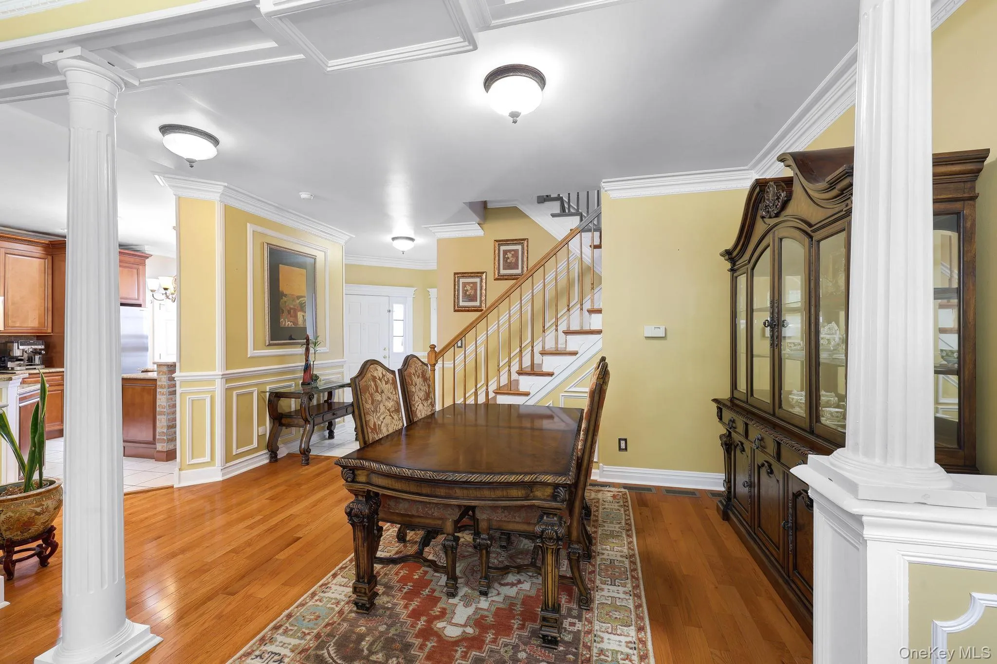 Hardwood flooring throughout featuring a visible staircase, decorative wall paneling, and crown molding Hardwood flooring throughout featuring a visible staircase, decorative wall paneling, and crown molding