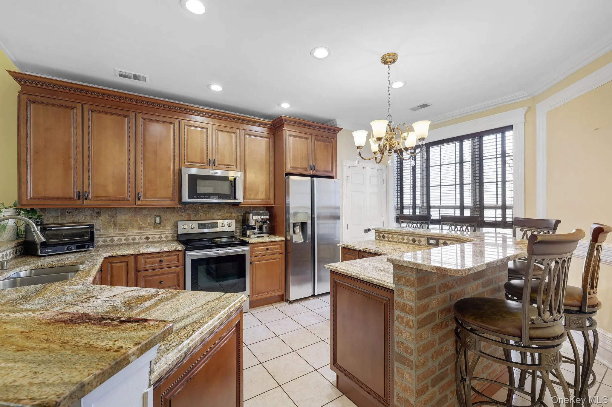 Kitchen featuring wood cabinetry, stainless steel appliances, granite countertops, and tile flooring Kitchen featuring wood cabinetry, stainless steel appliances, granite countertops, and tile flooring