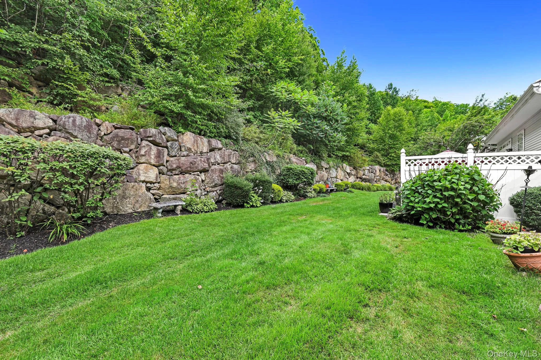 Expansive lawn area featuring a natural stone retaining wall Expansive lawn area featuring a natural stone retaining wall