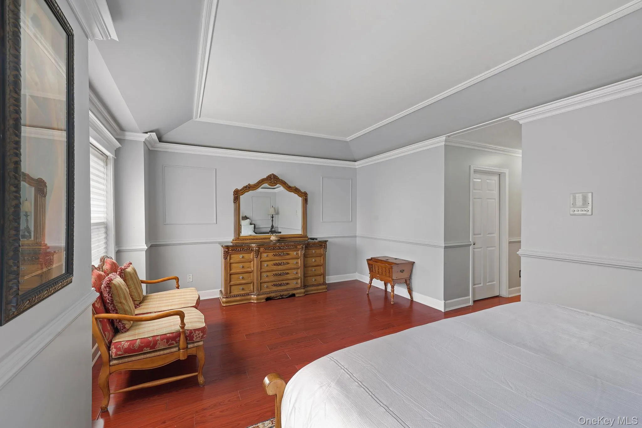 Room featuring wood-finish flooring, tray ceiling, crown molding, chair rail molding, and window with blinds Room featuring wood-finish flooring, tray ceiling, crown molding, chair rail molding, and window with blinds