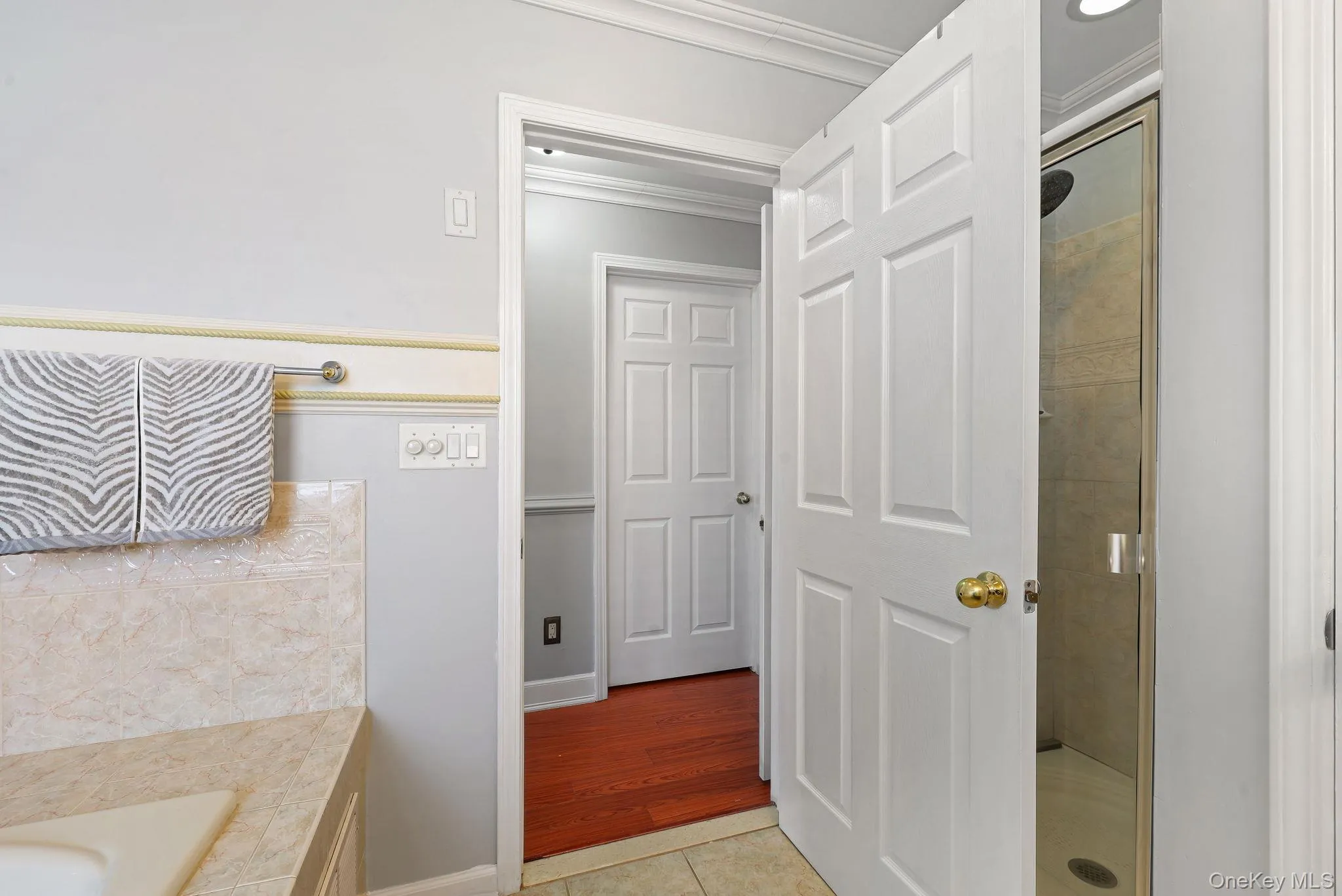 Bathroom featuring a glass-enclosed shower, tile flooring, and a vanity with a light-colored countertop Bathroom featuring a glass-enclosed shower, tile flooring, and a vanity with a light-colored countertop