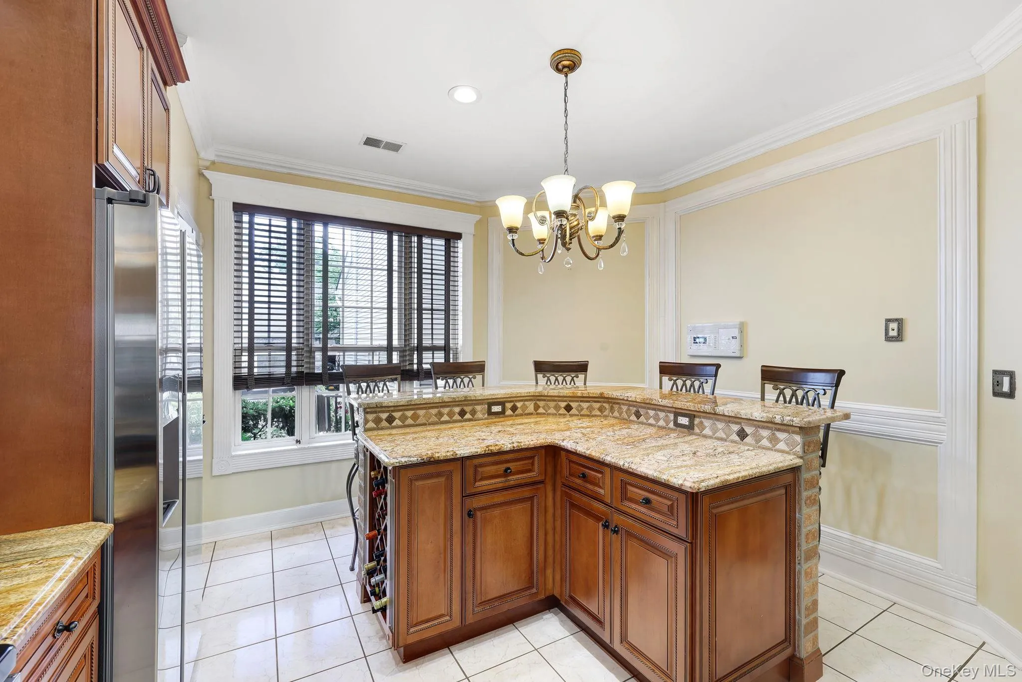 Kitchen island featuring a granite countertop, integrated tile backsplash, and rich wood cabinetry with a built-in wine rack Kitchen island featuring a granite countertop, integrated tile backsplash, and rich wood cabinetry with a built-in wine rack
