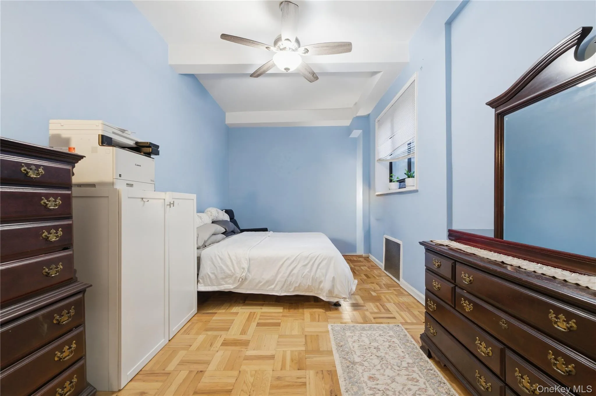Bedroom featuring light blue walls, parquet wood-finish flooring, a ceiling fan with integrated lighting, and a window with blinds Bedroom featuring light blue walls, parquet wood-finish flooring, a ceiling fan with integrated lighting, and a window with blinds