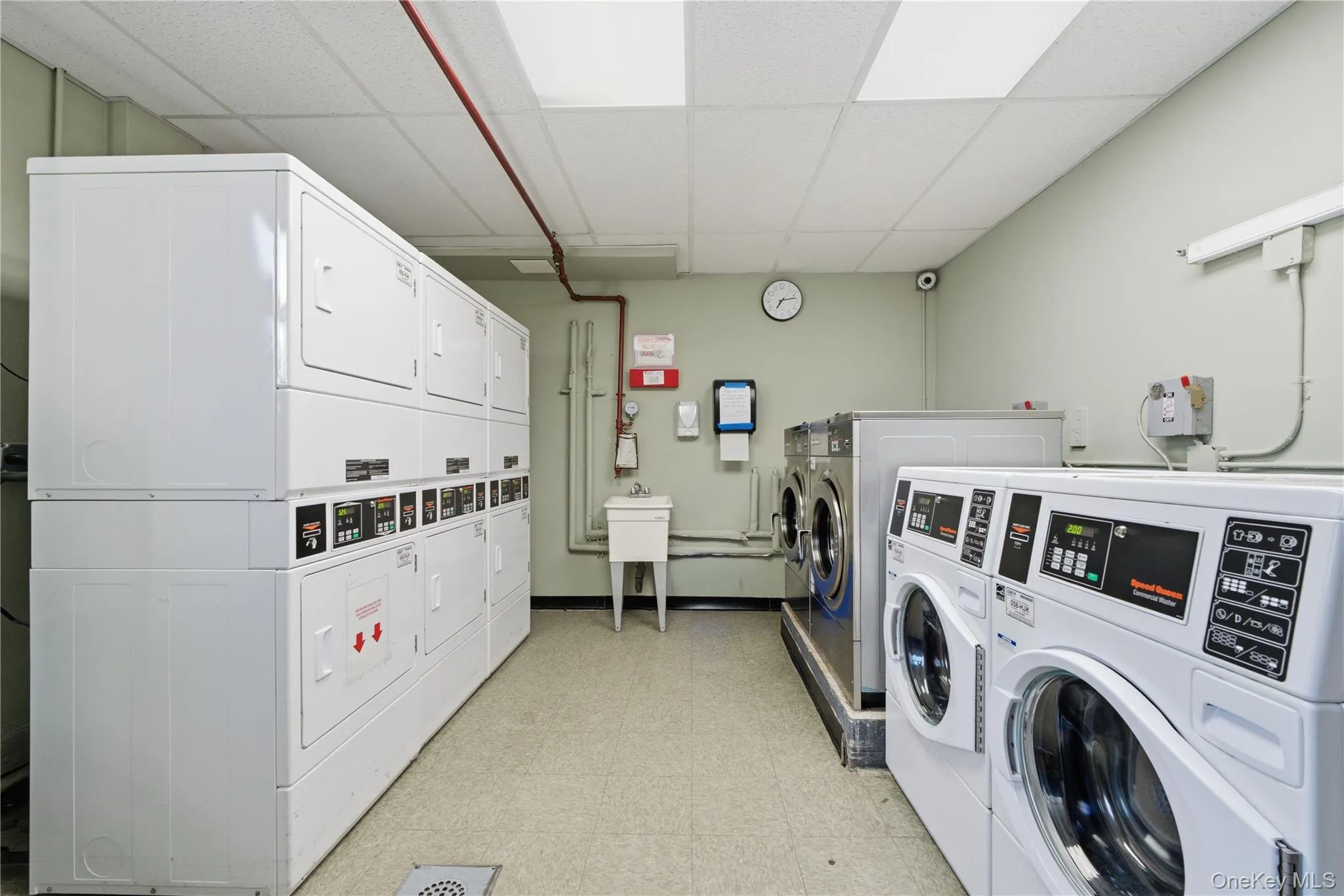 Two dedicated laundry rooms featuring multiple commercial-grade washers and dryers, a utility sink, and durable vinyl flooring Two dedicated laundry rooms featuring multiple commercial-grade washers and dryers, a utility sink, and durable vinyl flooring
