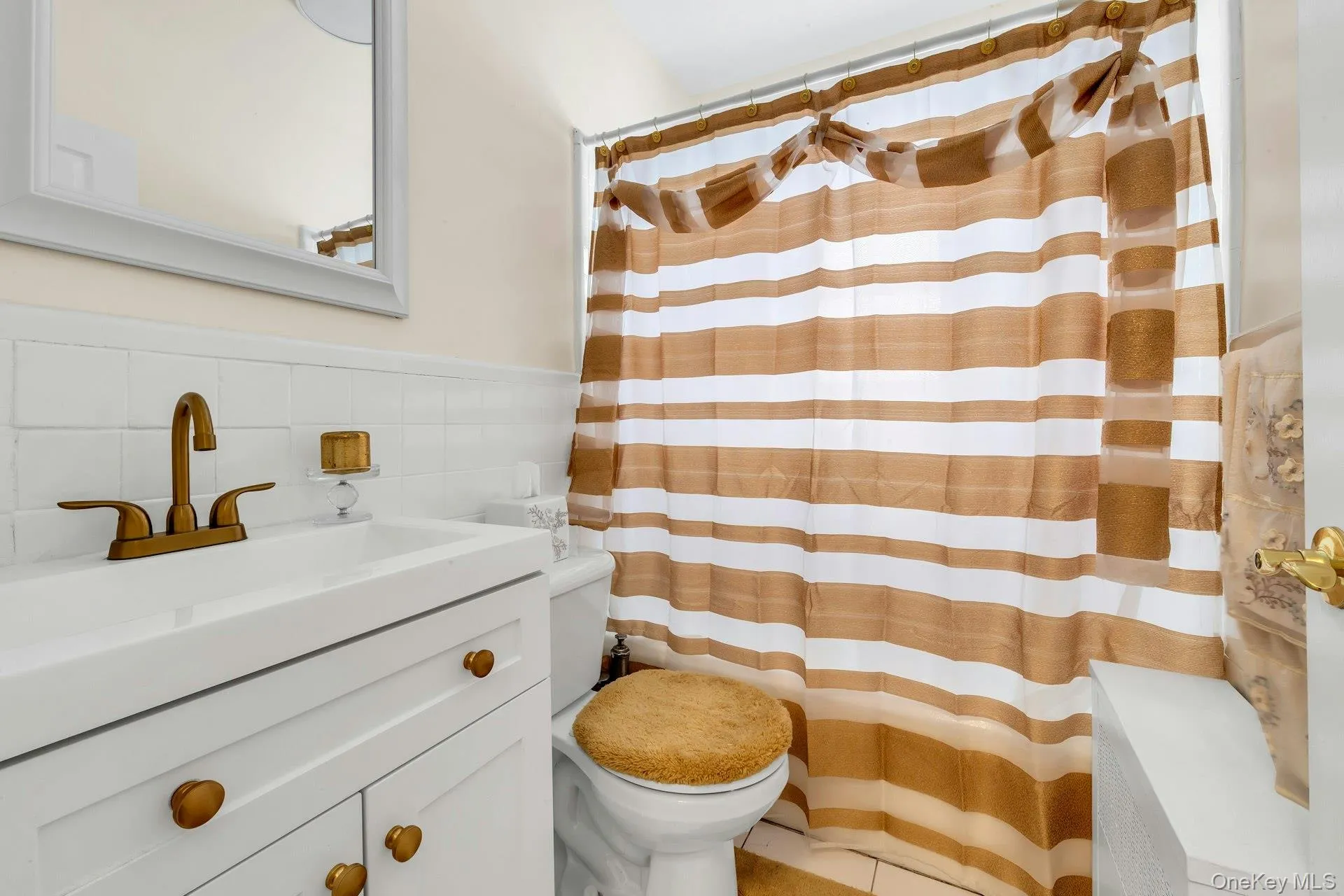 Bathroom featuring a white vanity with gold-toned hardware, a rectangular sink, and a matching gold-toned faucet Bathroom featuring a white vanity with gold-toned hardware, a rectangular sink, and a matching gold-toned faucet