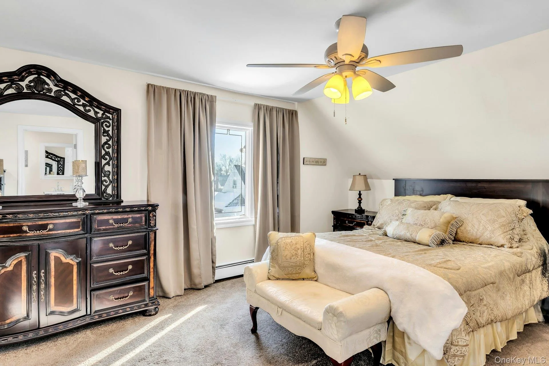 Carpeted room featuring a ceiling fan with integrated lighting, a window with drapery, and a dark wood-finish headboard Carpeted room featuring a ceiling fan with integrated lighting, a window with drapery, and a dark wood-finish headboard
