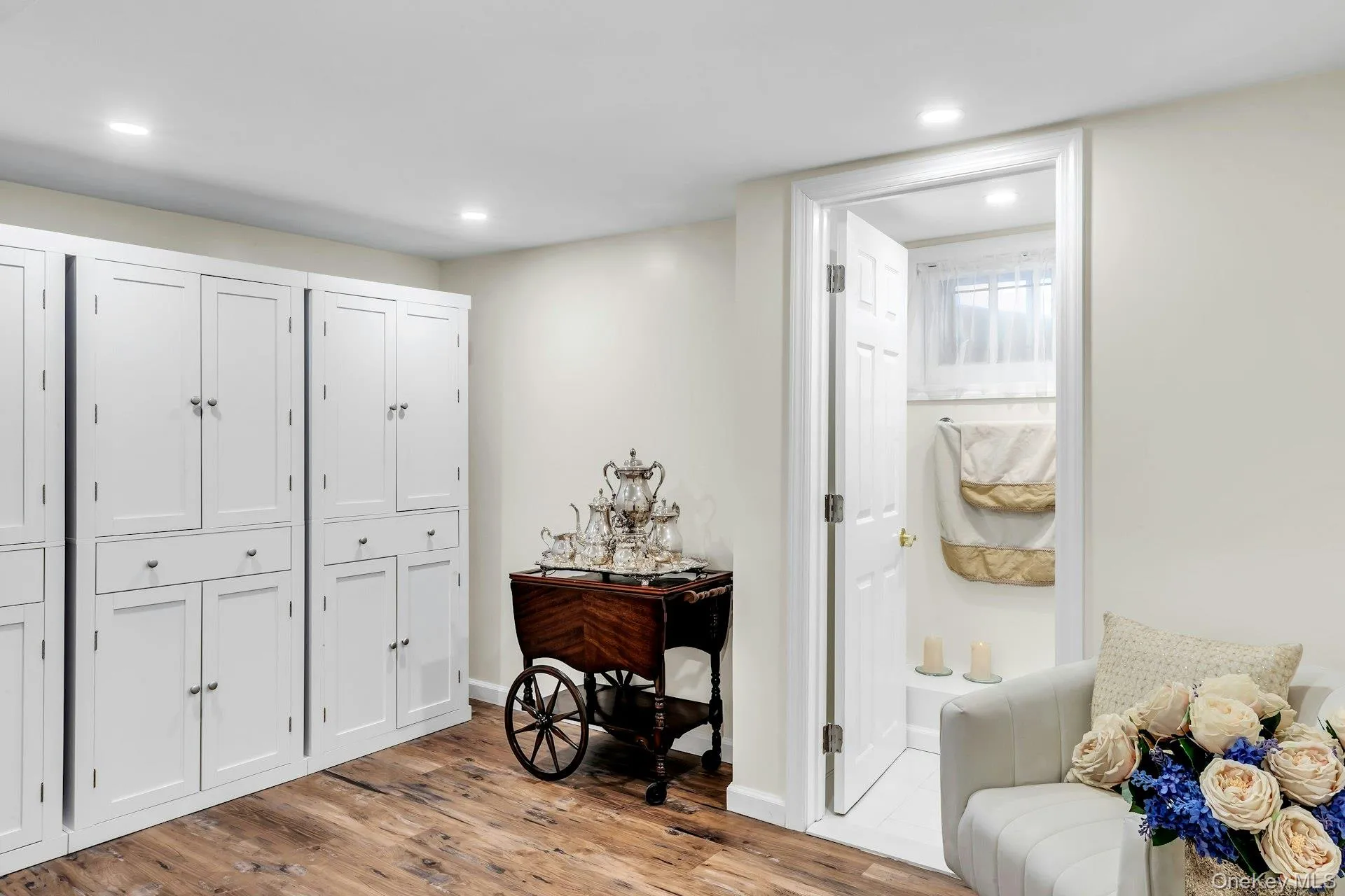 Recessed lighting illuminates the space, featuring extensive built-in white cabinetry with various door and drawer configurations Recessed lighting illuminates the space, featuring extensive built-in white cabinetry with various door and drawer configurations