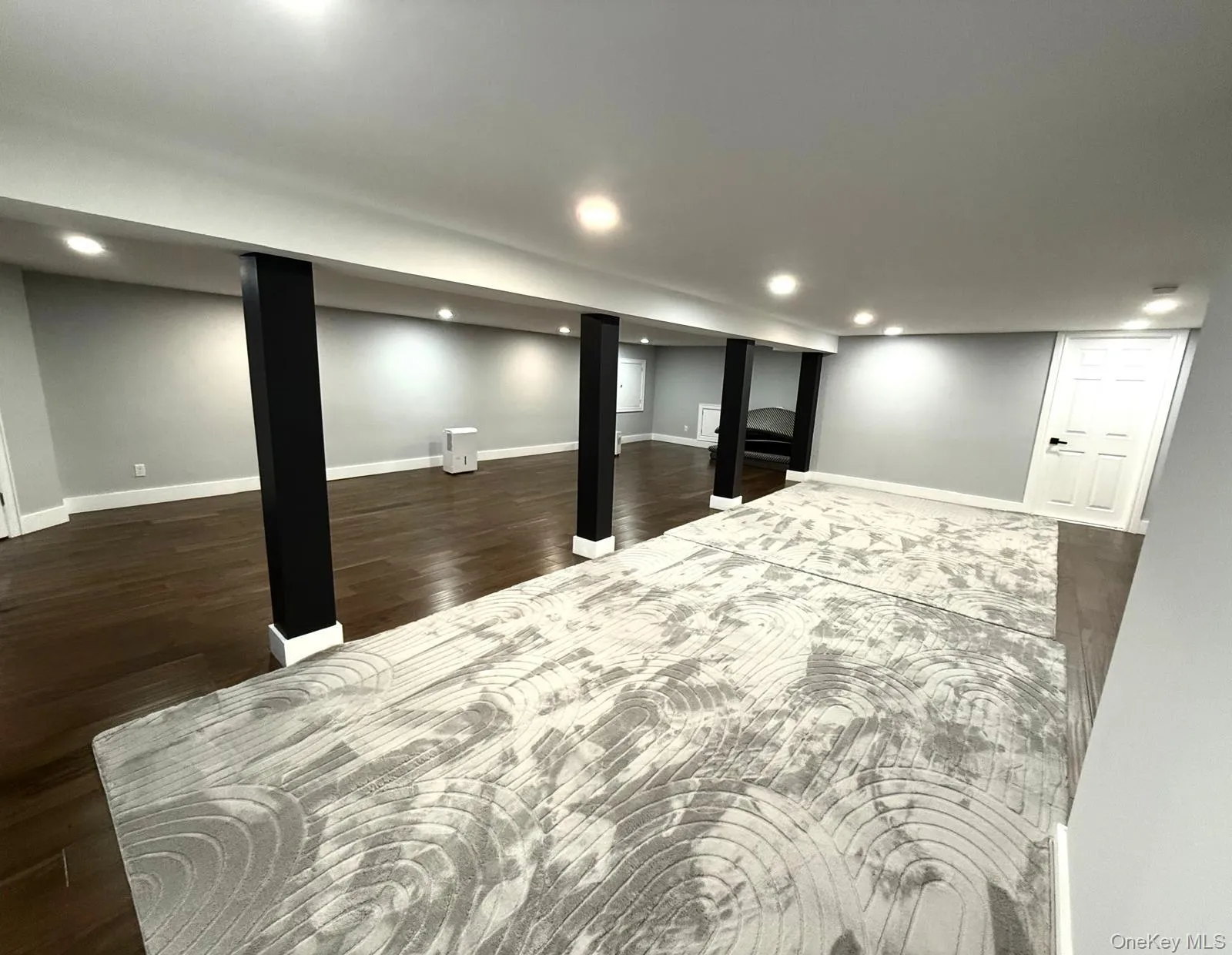 Spacious finished lower level featuring recessed lighting, dark wood-finish flooring, light gray walls Spacious finished lower level featuring recessed lighting, dark wood-finish flooring, light gray walls