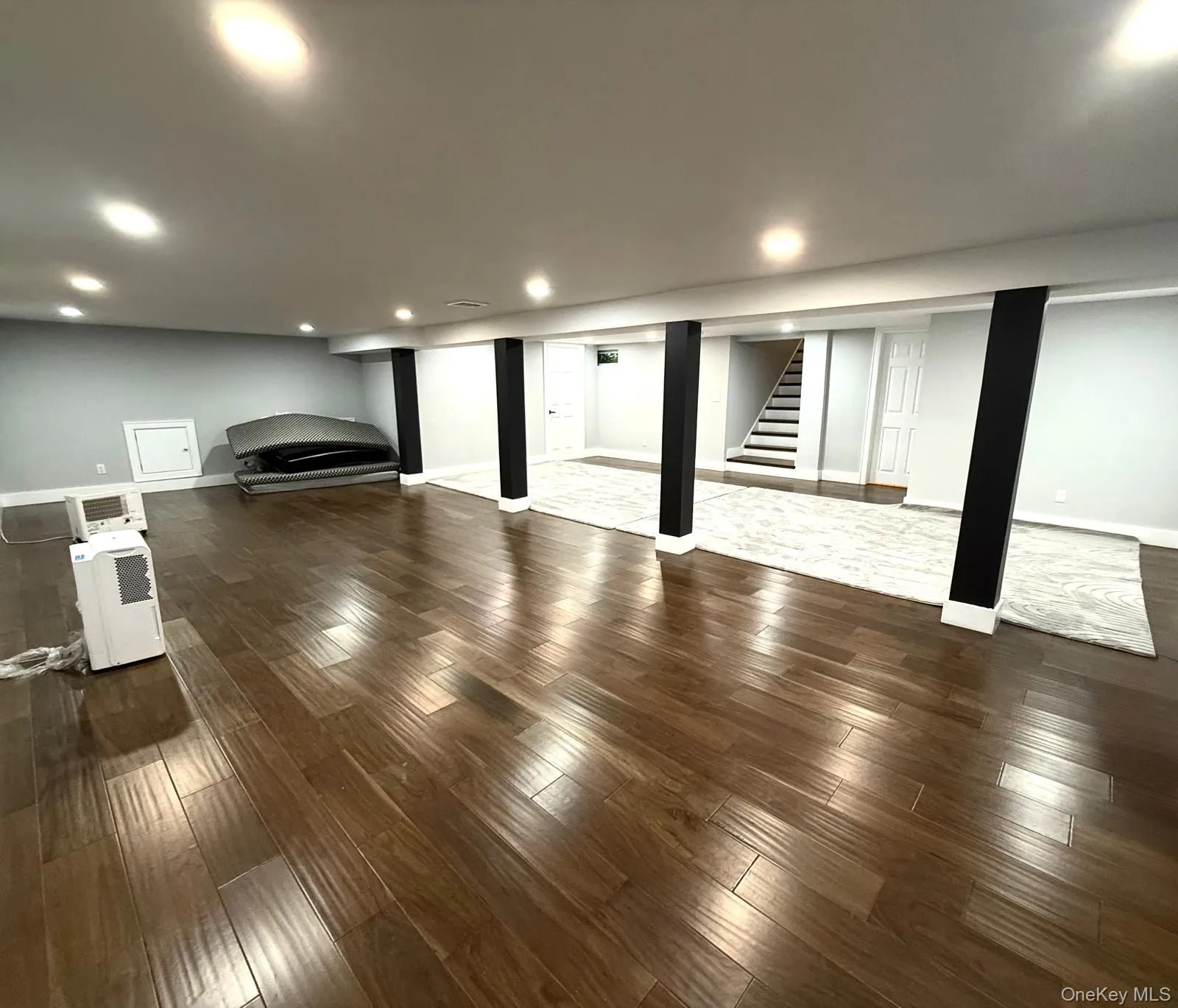 Spacious finished lower level featuring recessed lighting, dark wood-finish flooring, and light-toned walls Spacious finished lower level featuring recessed lighting, dark wood-finish flooring, and light-toned walls