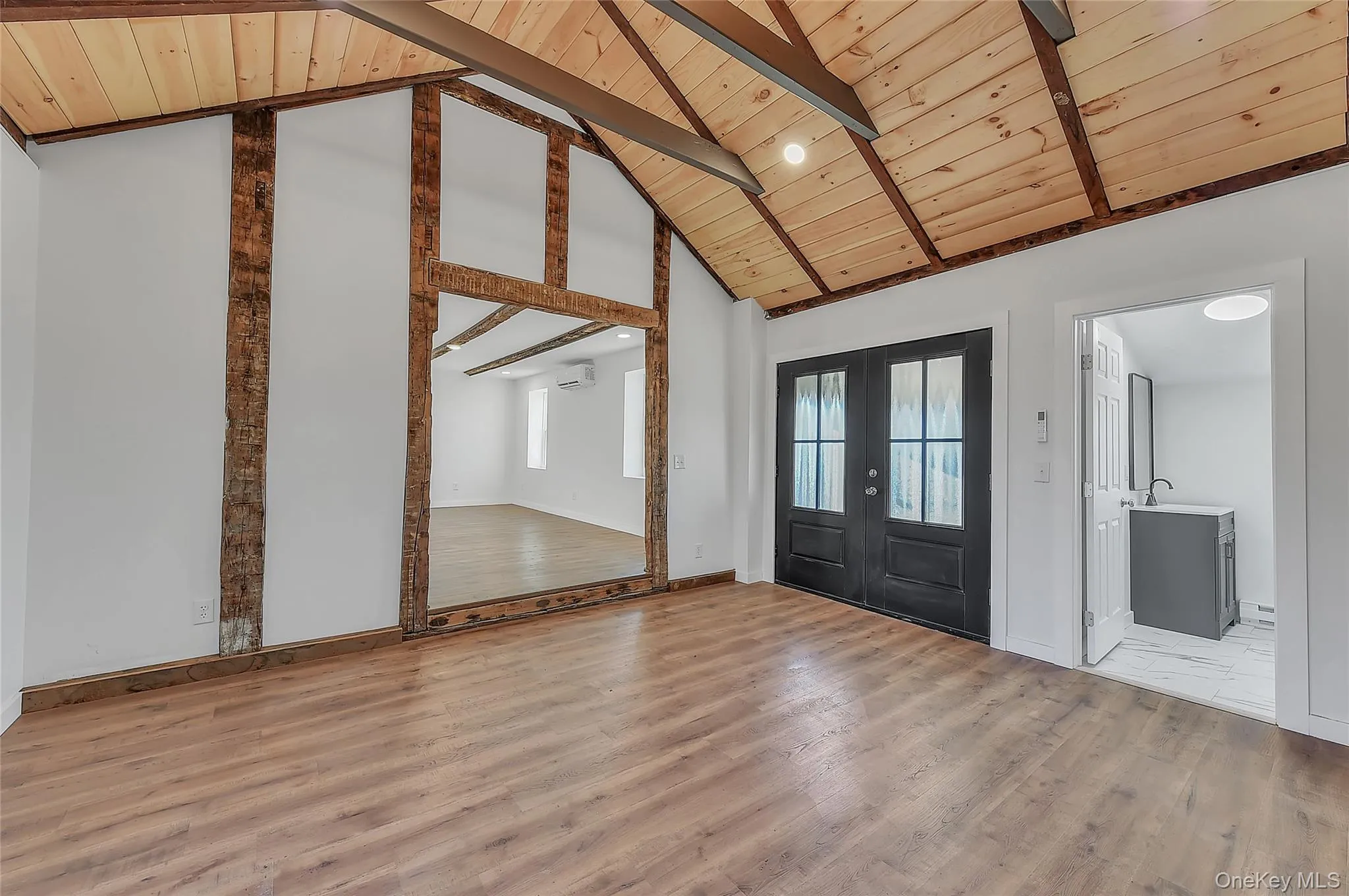 Foyer entrance featuring french doors, light wood-style floors, high vaulted ceiling, and a wooden ceiling with exposed beams Foyer entrance featuring french doors, light wood-style floors, high vaulted ceiling, and a wooden ceiling with exposed beams