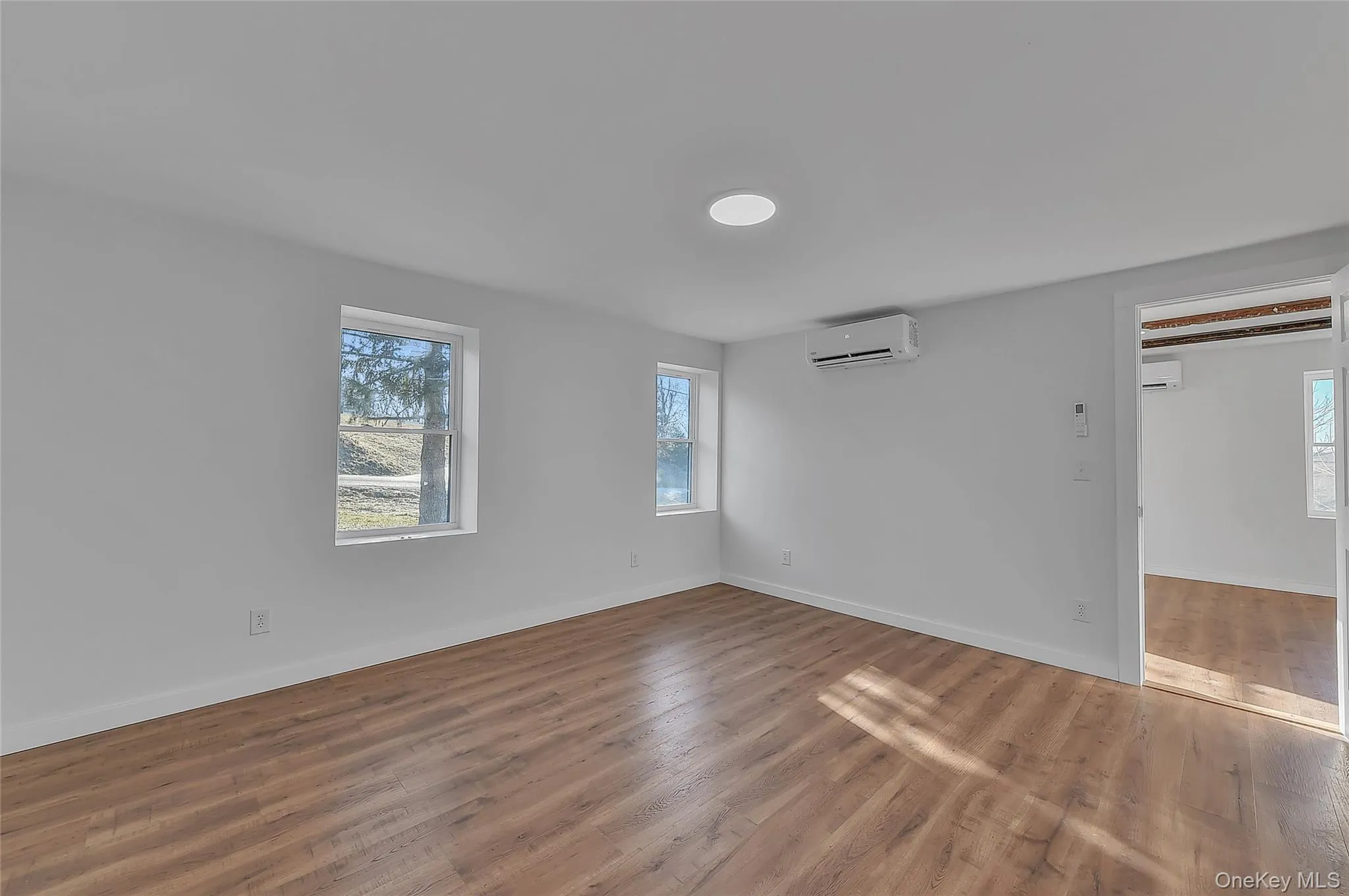 Unfurnished room featuring wood finished floors and a wall mounted AC Unfurnished room featuring wood finished floors and a wall mounted AC