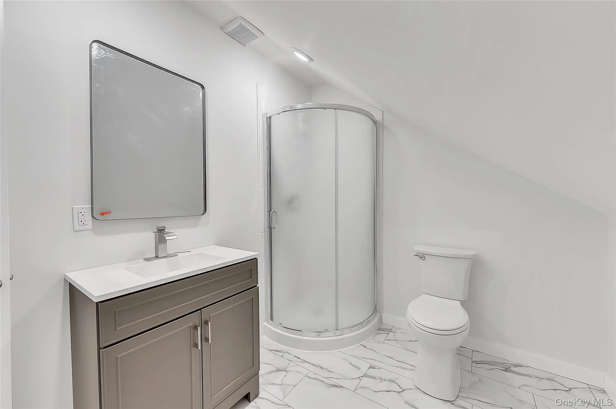 Full bath featuring light marble finish flooring, vanity, a stall shower, and vaulted ceiling Full bath featuring light marble finish flooring, vanity, a stall shower, and vaulted ceiling
