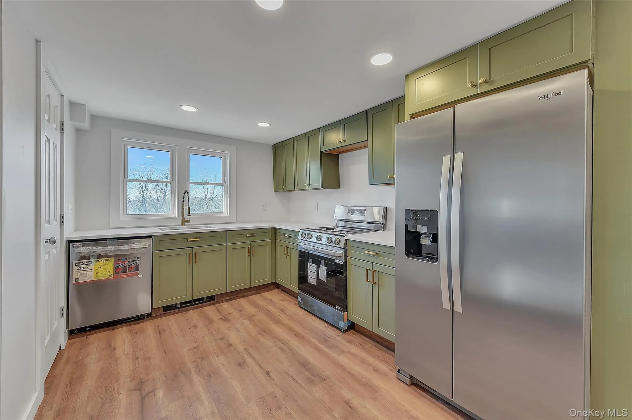 Kitchen featuring green cabinets, stainless steel appliances, light wood finished floors, and recessed lighting Kitchen featuring green cabinets, stainless steel appliances, light wood finished floors, and recessed lighting
