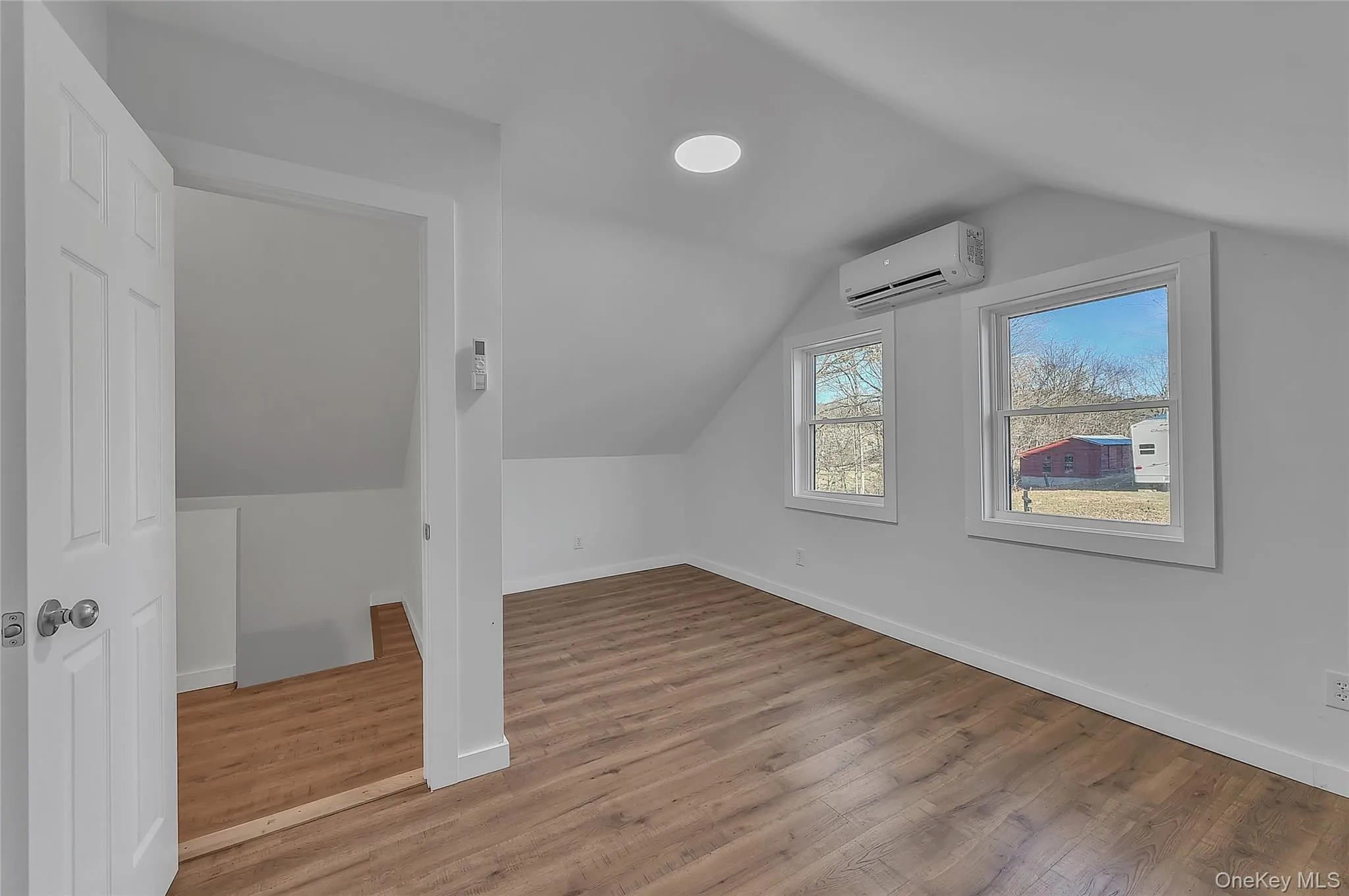 Additional living space with vaulted ceiling, light wood-style floors, and a wall unit AC Additional living space with vaulted ceiling, light wood-style floors, and a wall unit AC