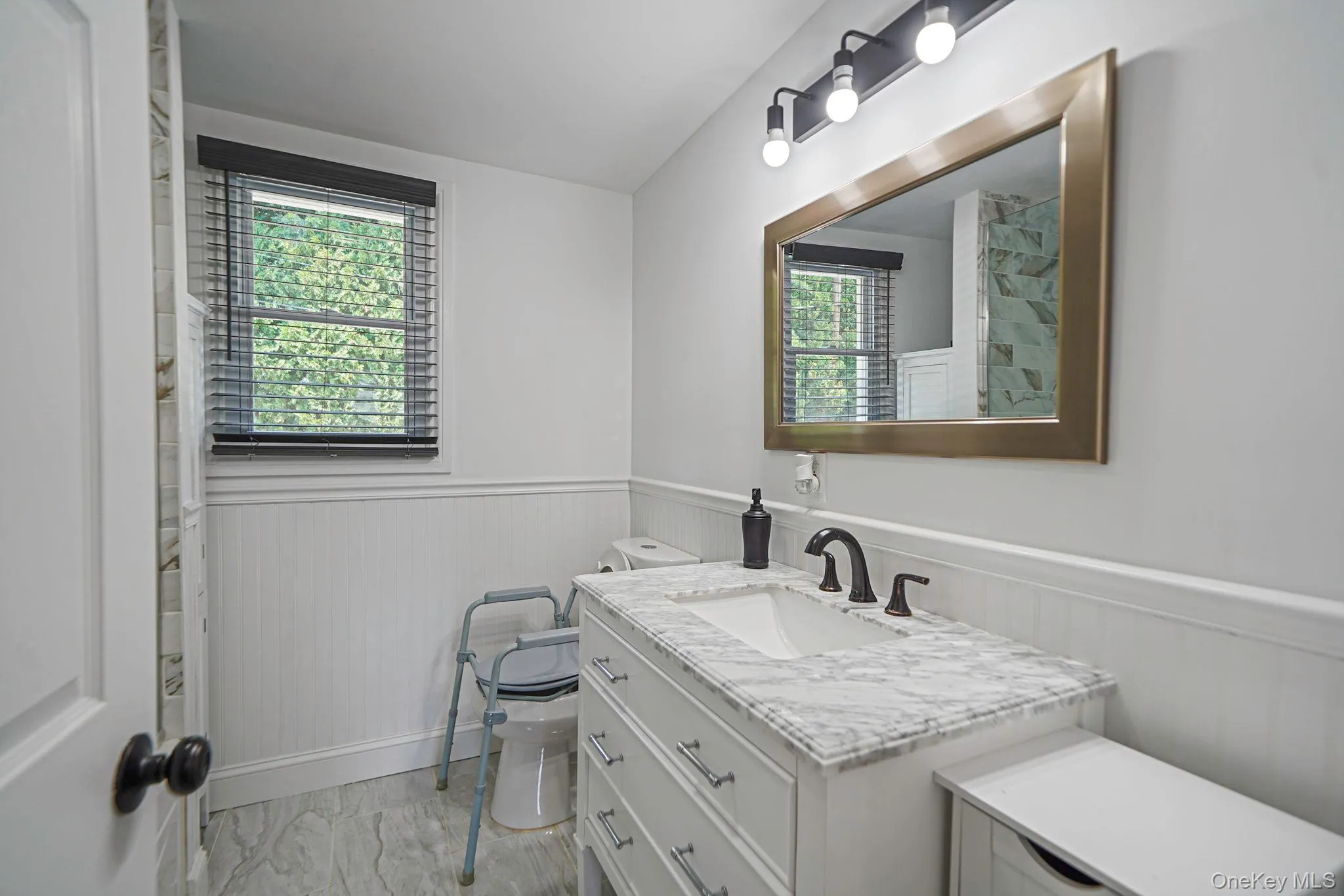 Bathroom with marble look tiles, wainscoting, and vanity Bathroom with marble look tiles, wainscoting, and vanity