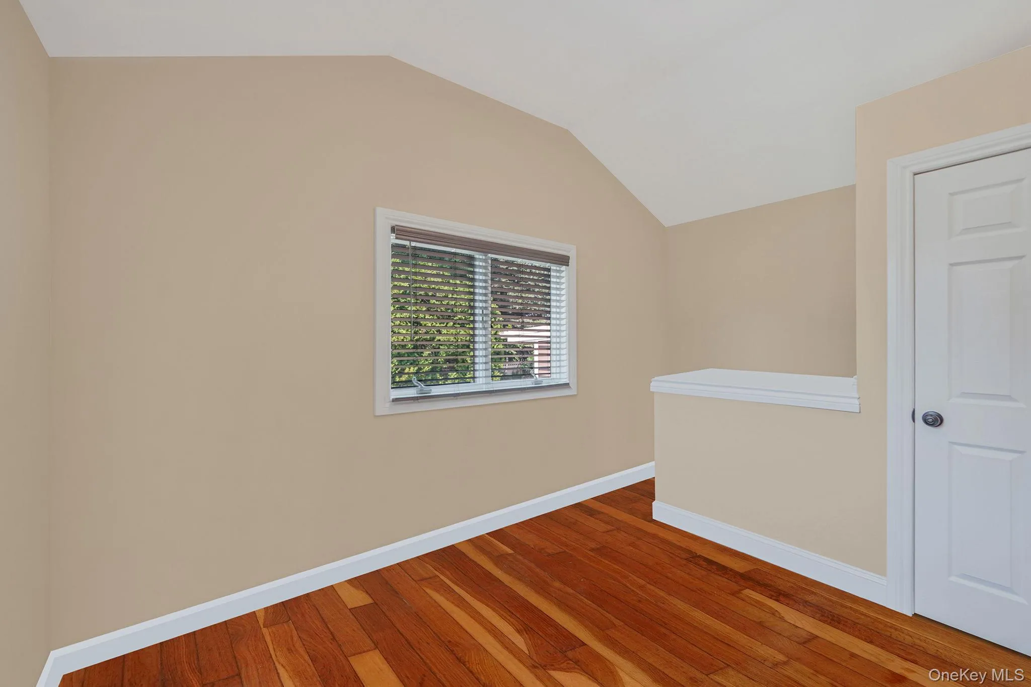 Empty room with wood finished floors and vaulted ceiling Empty room with wood finished floors and vaulted ceiling