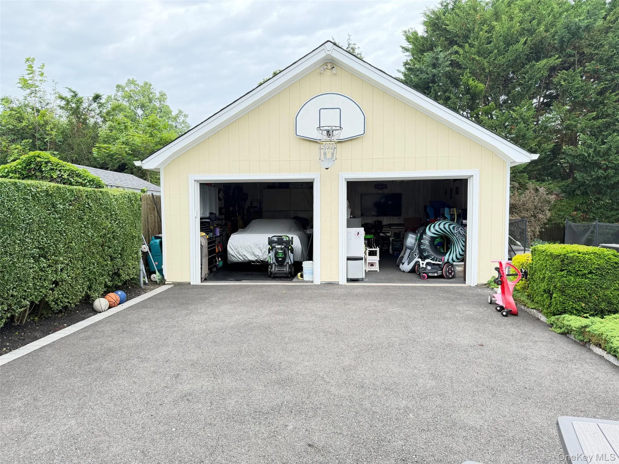 Two-bay garage with light yellow siding, white trim, and an asphalt driveway Two-bay garage with light yellow siding, white trim, and an asphalt driveway