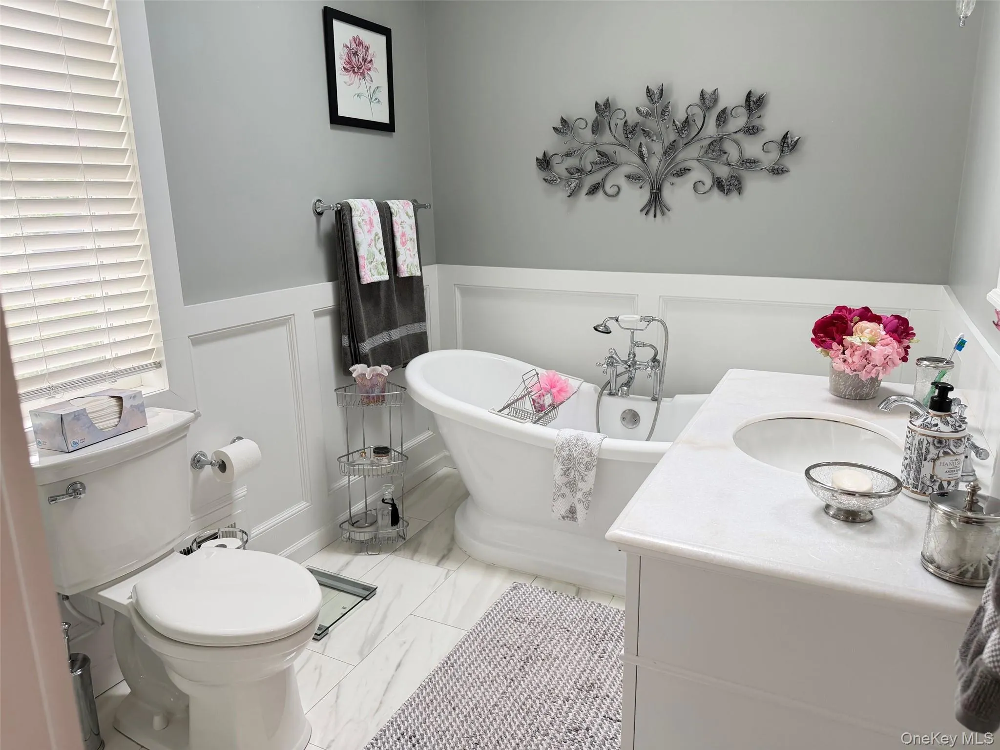 White freestanding soaking tub paired with a white vanity featuring a stone countertop and an undermount sink White freestanding soaking tub paired with a white vanity featuring a stone countertop and an undermount sink