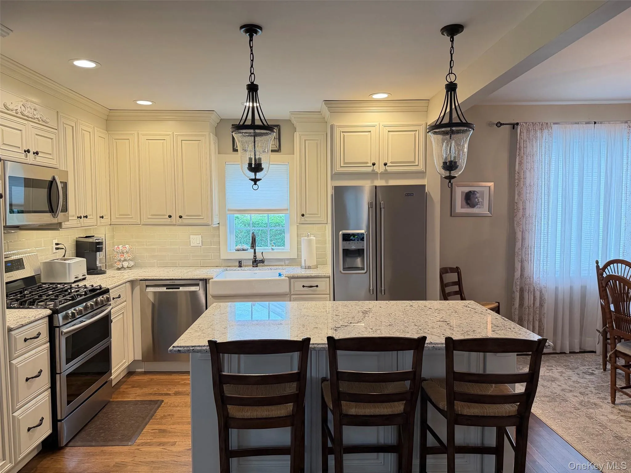 Kitchen featuring a center island, light-toned cabinetry, stainless steel appliances, a farmhouse sink, and recessed lighting Kitchen featuring a center island, light-toned cabinetry, stainless steel appliances, a farmhouse sink, and recessed lighting