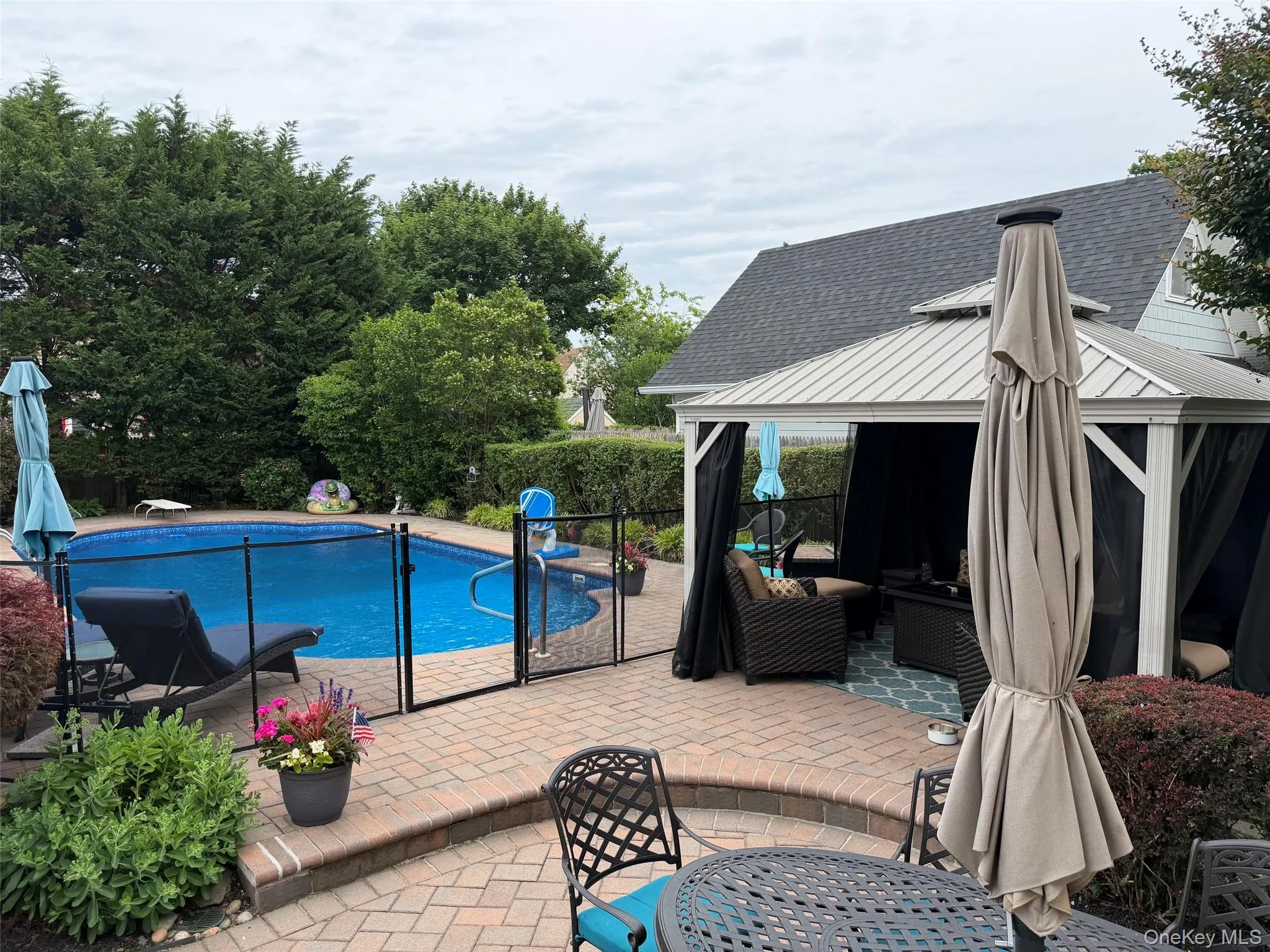 Expansive outdoor living area featuring a paved brick patio, fenced inground pool, and shaded gazebo Expansive outdoor living area featuring a paved brick patio, fenced inground pool, and shaded gazebo