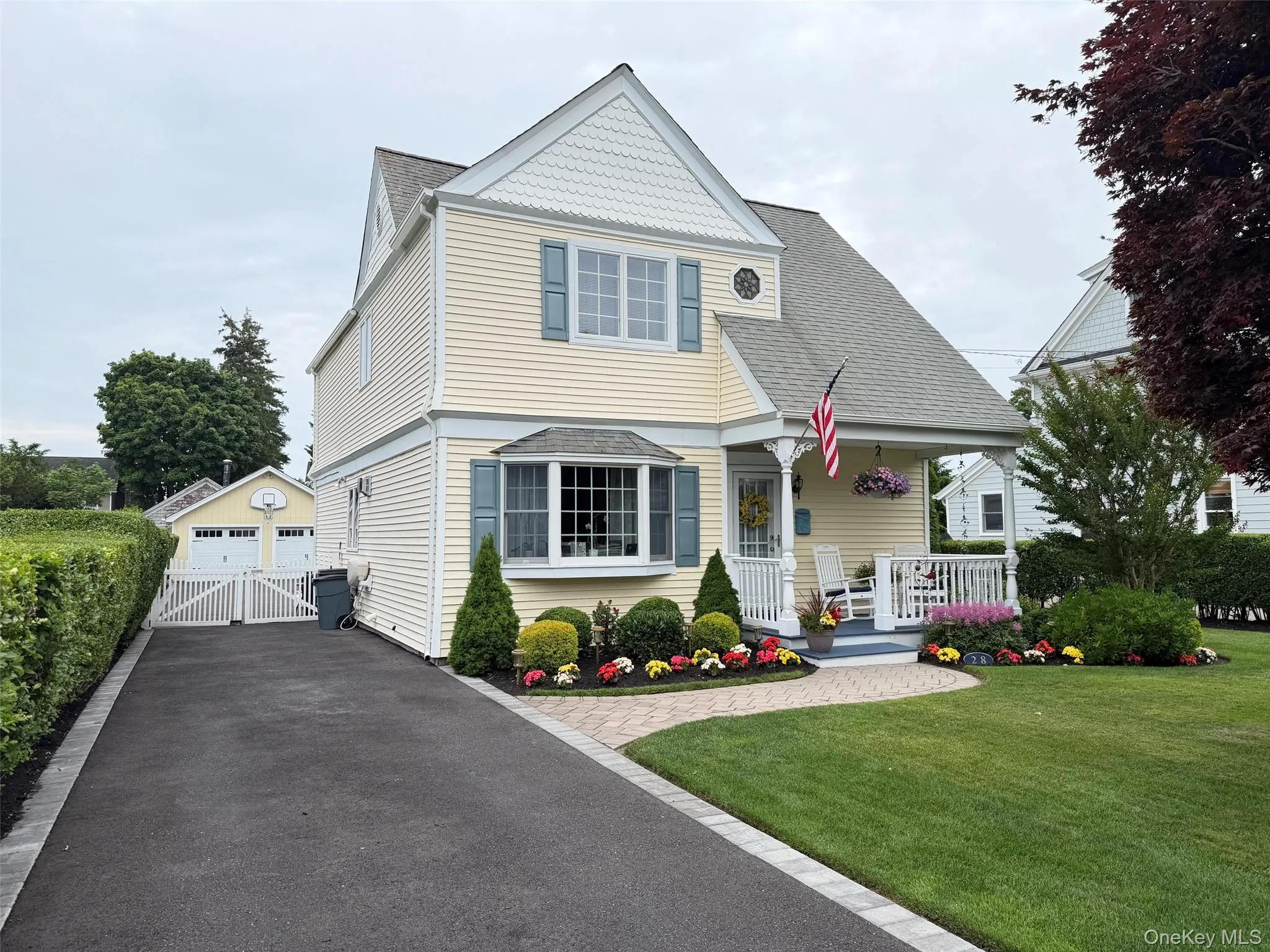 Yellow siding residence featuring a covered front porch, bay window, and a two-car detached garage Yellow siding residence featuring a covered front porch, bay window, and a two-car detached garage
