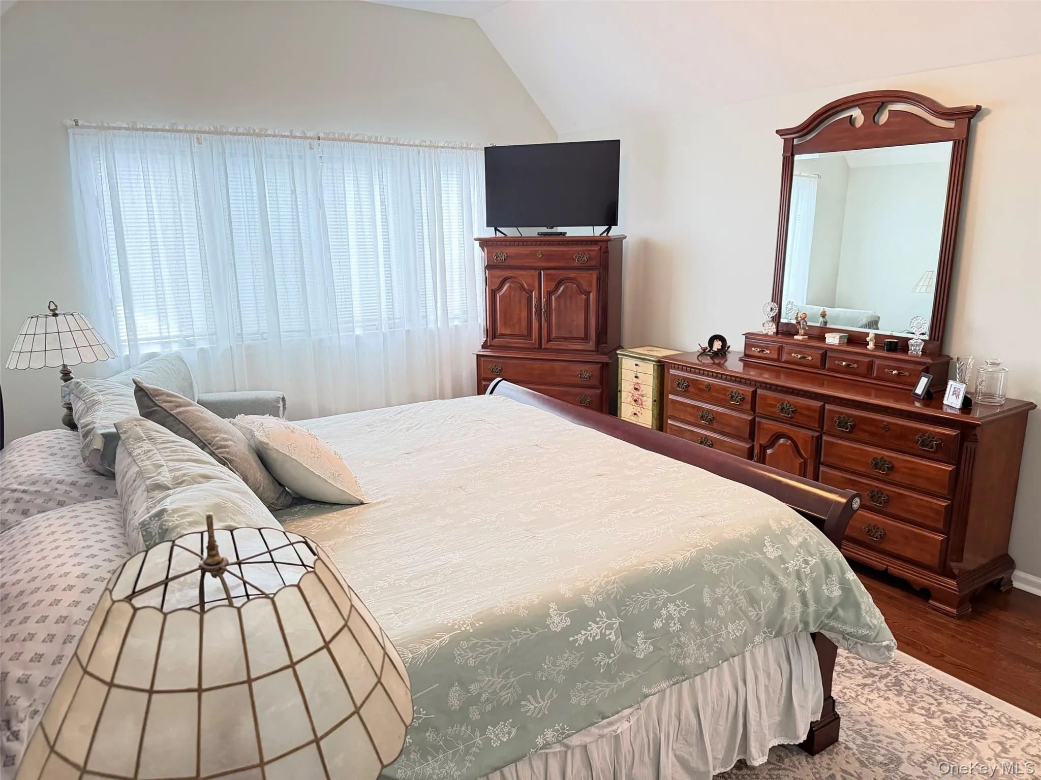 Vaulted ceiling bedroom with a large window featuring privacy blinds and sheer curtains Vaulted ceiling bedroom with a large window featuring privacy blinds and sheer curtains