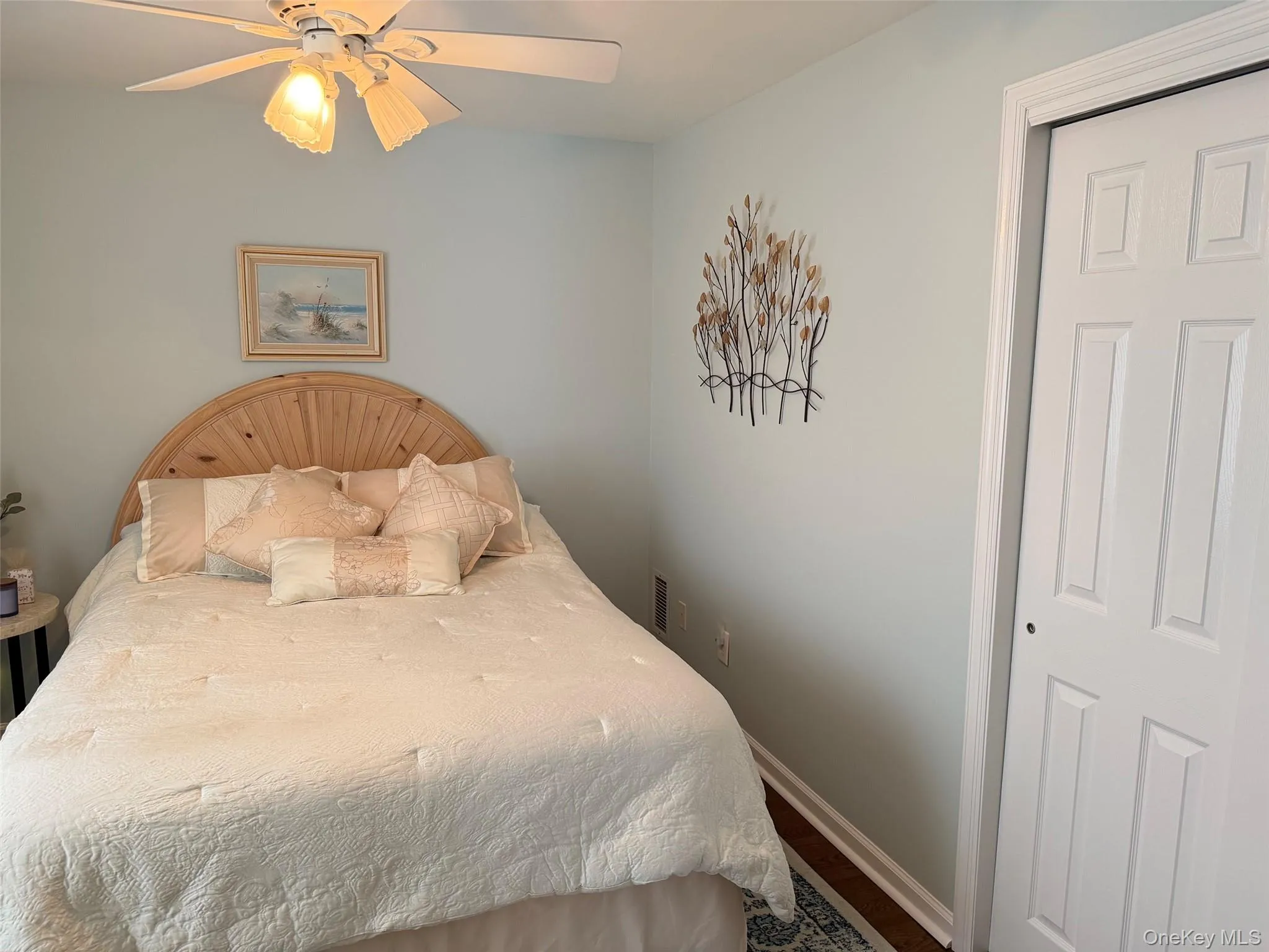 Bedroom featuring a ceiling fan with integrated lighting, wood-finish flooring, and light-colored walls Bedroom featuring a ceiling fan with integrated lighting, wood-finish flooring, and light-colored walls