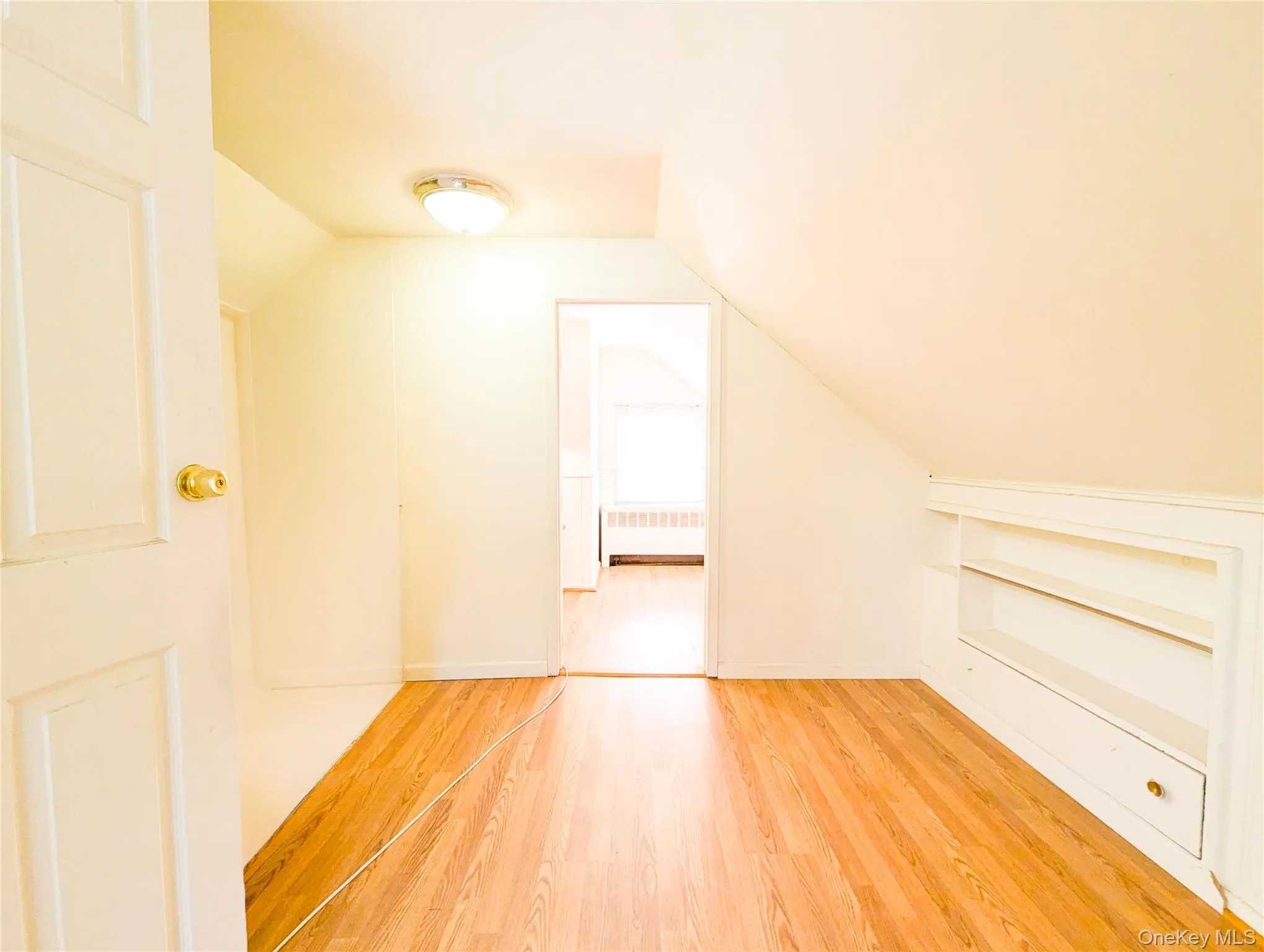 Additional living space featuring radiator heating unit, lofted ceiling, and wood-type flooring Additional living space featuring radiator heating unit, lofted ceiling, and wood-type flooring