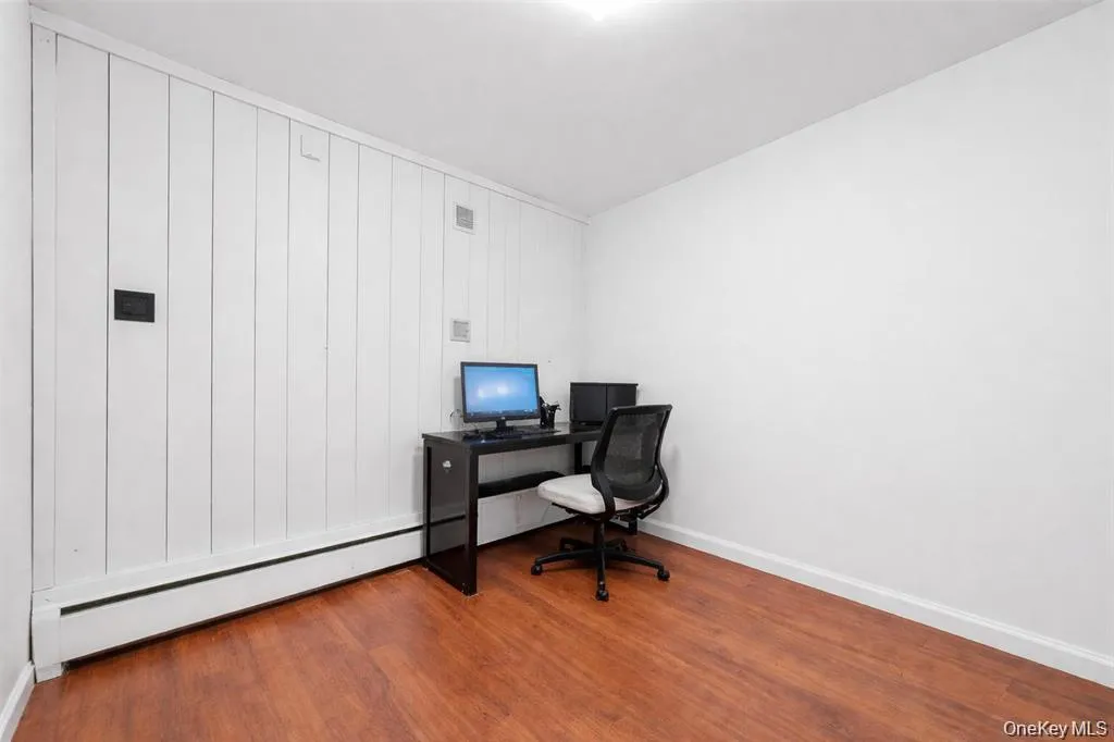 Home office with light wood-type flooring and a baseboard radiator Home office with light wood-type flooring and a baseboard radiator