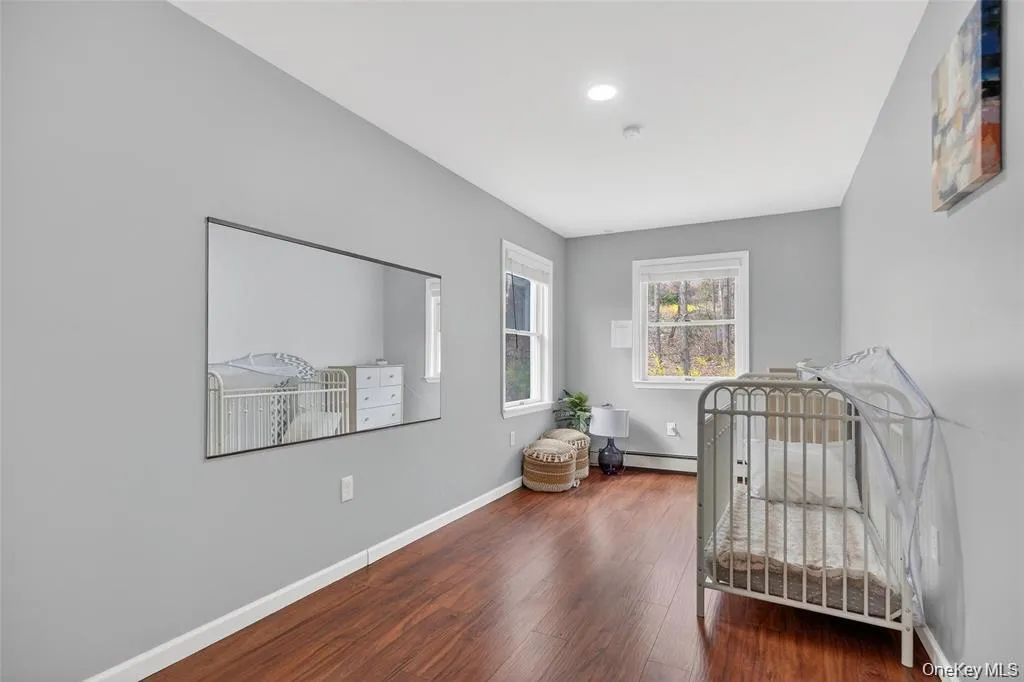Bedroom featuring a nursery area, wood finished floors, and a baseboard heating unit Bedroom featuring a nursery area, wood finished floors, and a baseboard heating unit