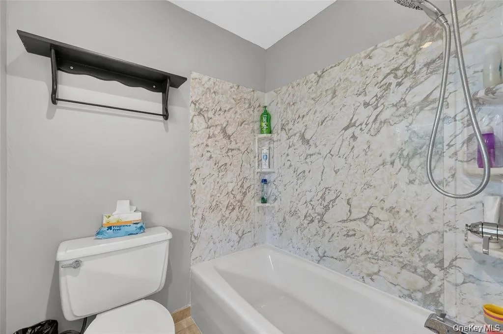 Bathroom with toilet and a combined bath / shower with marble appearance Bathroom with toilet and a combined bath / shower with marble appearance