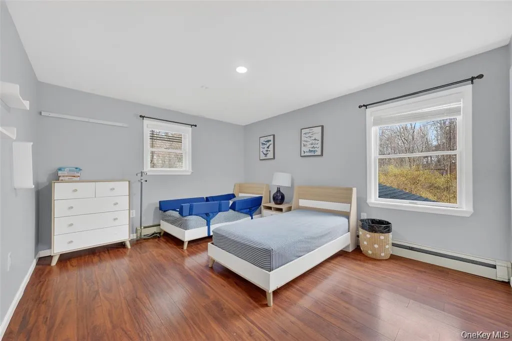 Bedroom with a baseboard heating unit, dark wood-style floors, baseboard heating, and recessed lighting Bedroom with a baseboard heating unit, dark wood-style floors, baseboard heating, and recessed lighting