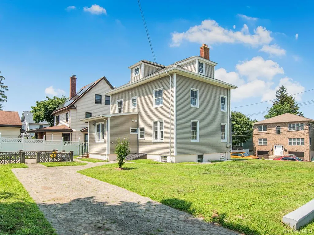 Three-story residential structure featuring light-toned siding and multiple windows Three-story residential structure featuring light-toned siding and multiple windows