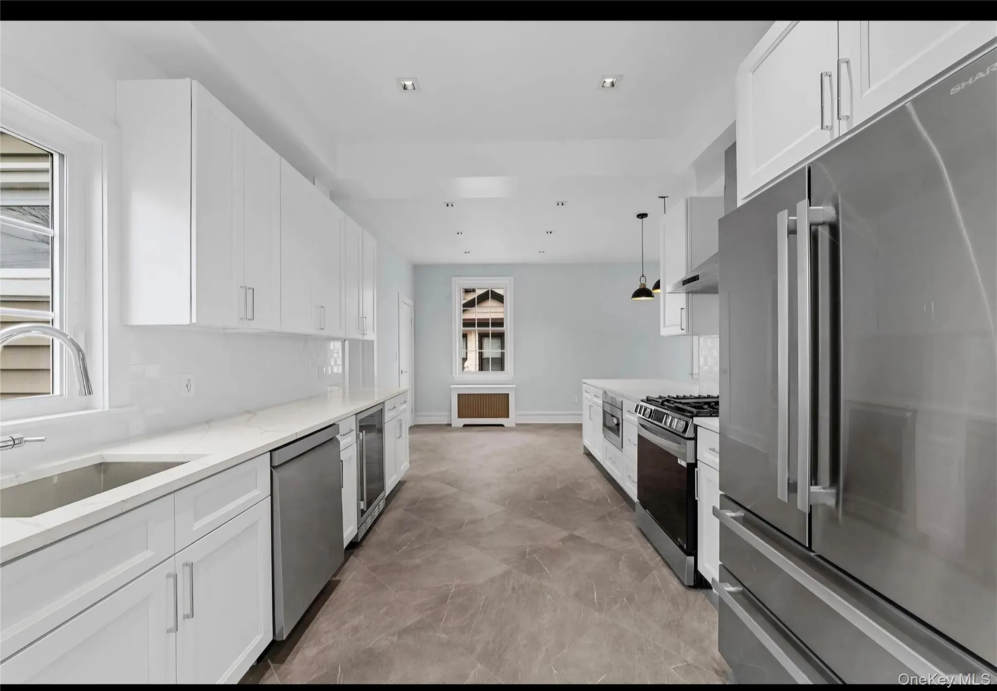 Modern kitchen featuring white shaker cabinetry, stainless steel appliances, and a tile backsplash Modern kitchen featuring white shaker cabinetry, stainless steel appliances, and a tile backsplash
