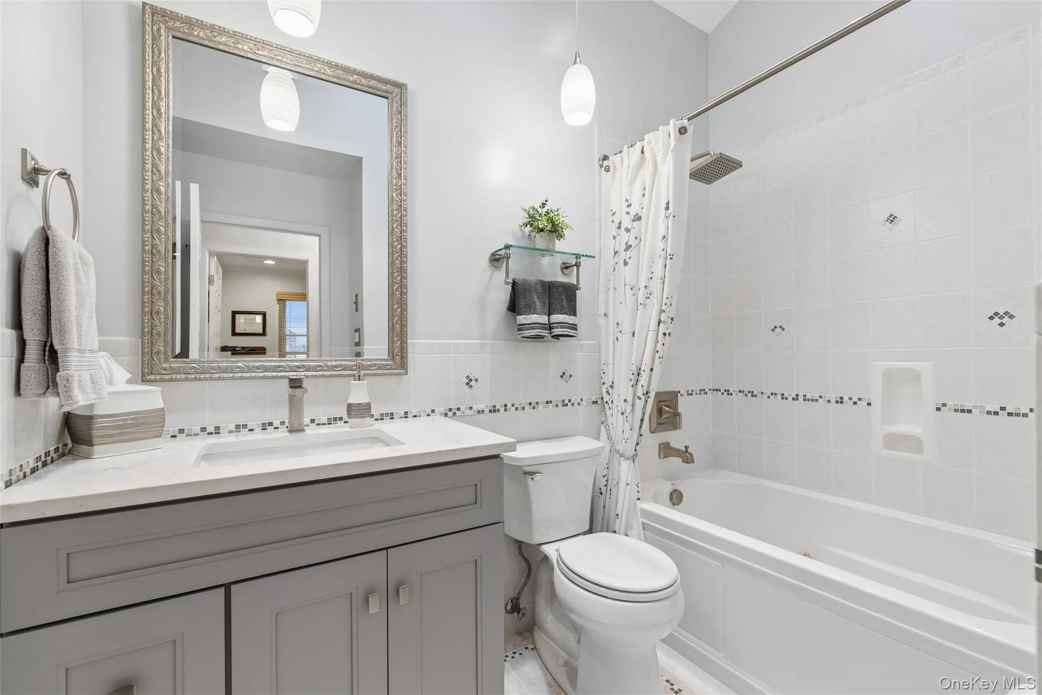 Bathroom featuring a single vanity with gray cabinetry, a white countertop, and an undermount sink. Jacuzzi tub Bathroom featuring a single vanity with gray cabinetry, a white countertop, and an undermount sink. Jacuzzi tub