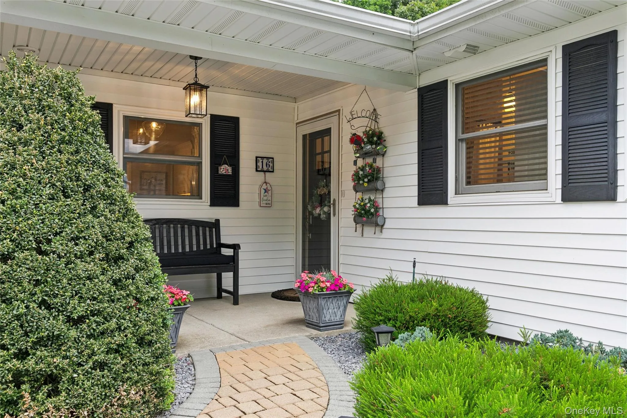 Covered front entry featuring white siding and black louvered shutters Covered front entry featuring white siding and black louvered shutters