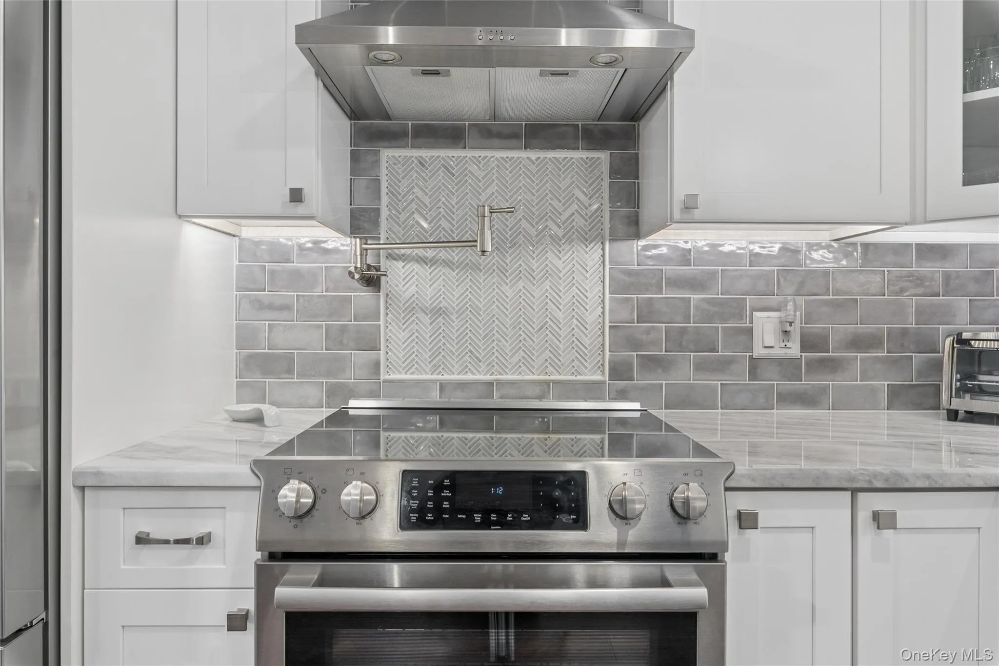 Stainless steel range with a built-in oven and a glass cooktop, complemented by a stainless steel range hood Stainless steel range with a built-in oven and a glass cooktop, complemented by a stainless steel range hood