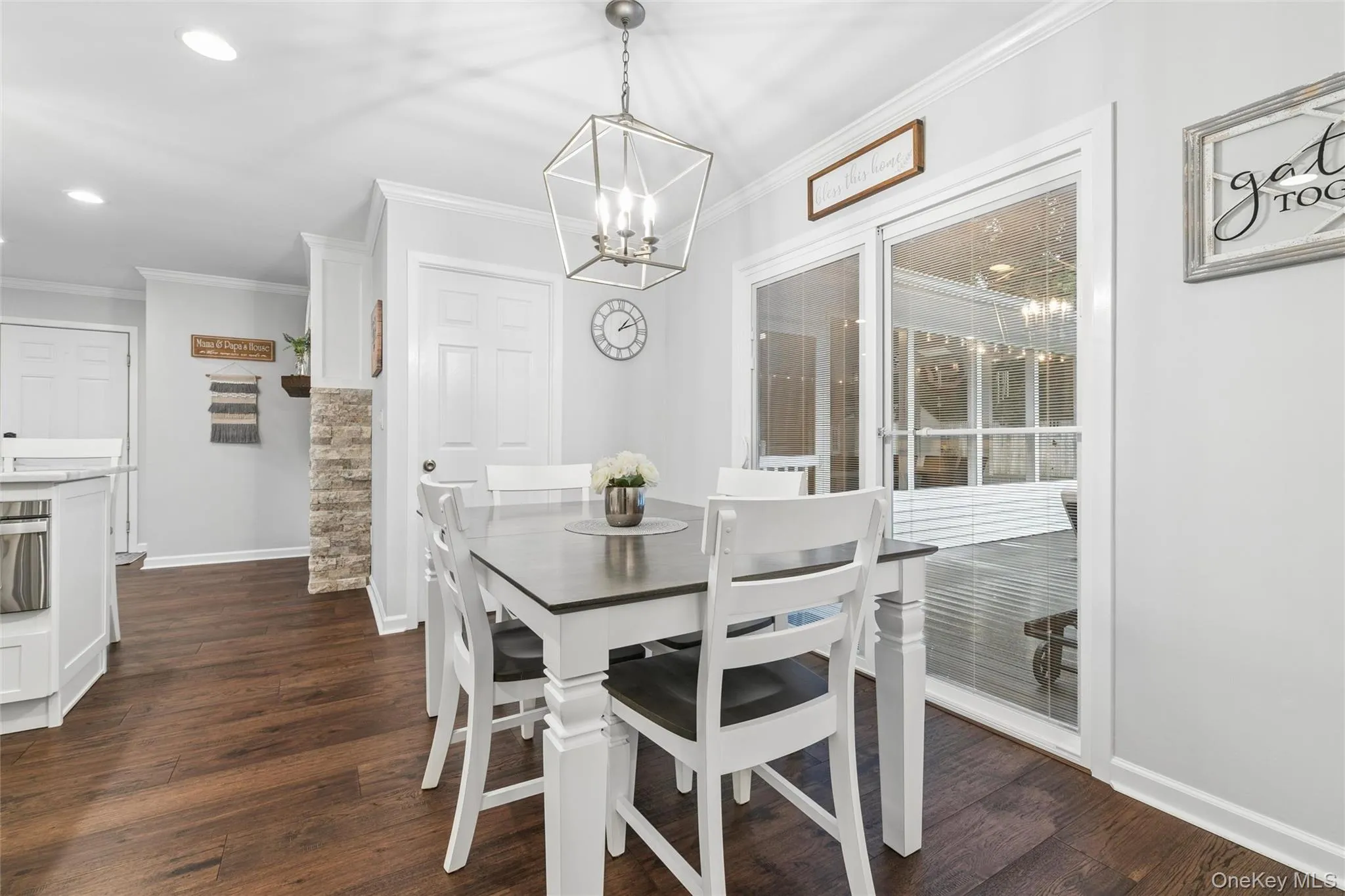 Dining area with wood-finish flooring, featuring a contemporary geometric chandelier, white trim work, and glass sliding doors Dining area with wood-finish flooring, featuring a contemporary geometric chandelier, white trim work, and glass sliding doors