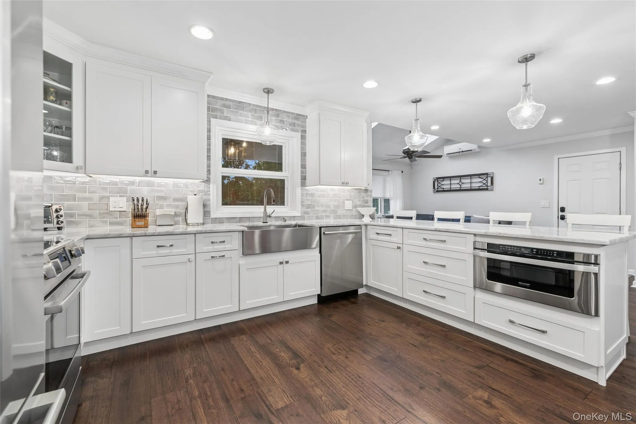 Kitchen featuring white shaker cabinetry, stainless steel appliances, wood-finish flooring, and light gray subway tile backsplash Kitchen featuring white shaker cabinetry, stainless steel appliances, wood-finish flooring, and light gray subway tile backsplash