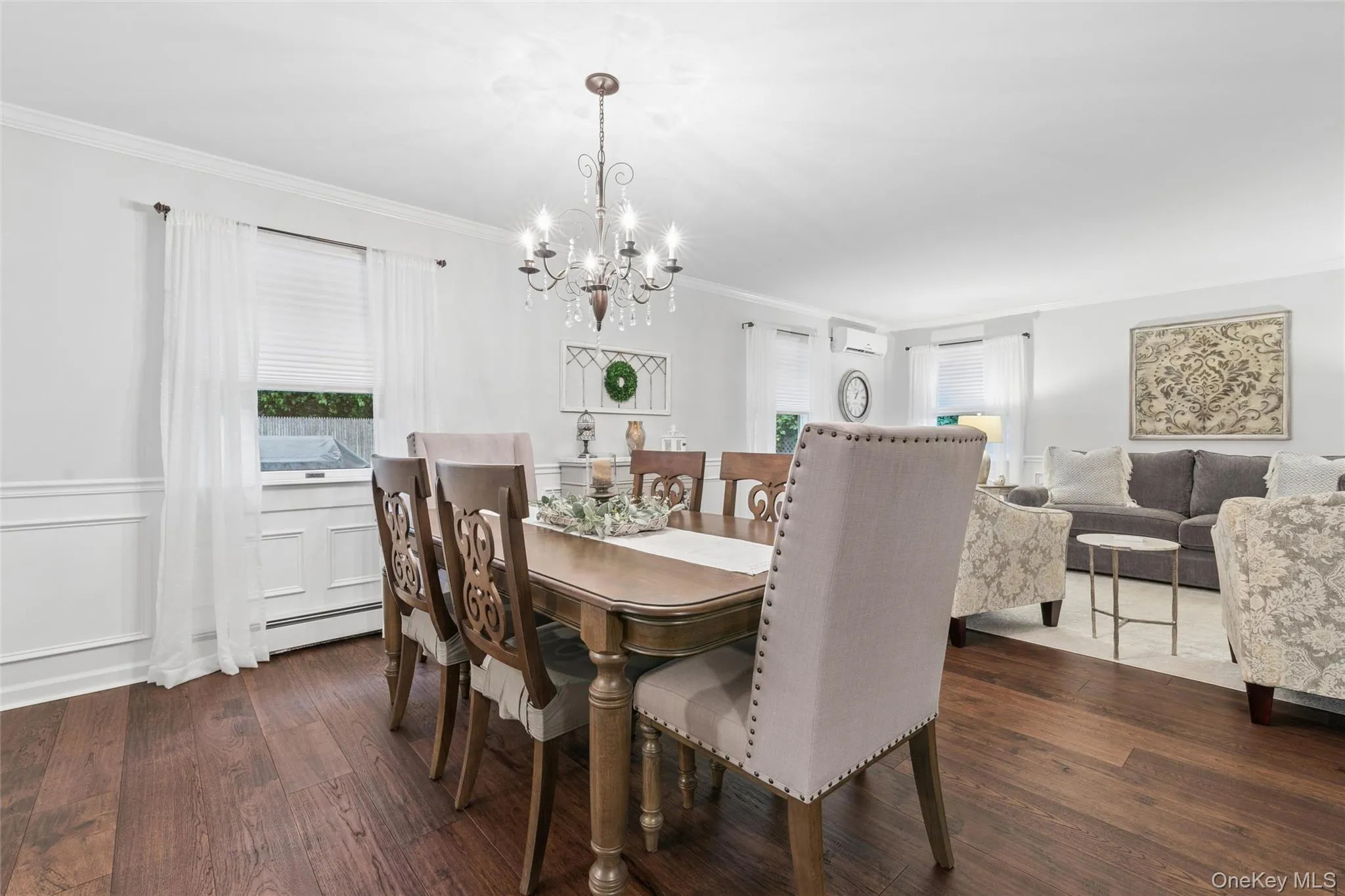 Wood-finish flooring throughout, featuring a dining area with a chandelier and wainscoting Wood-finish flooring throughout, featuring a dining area with a chandelier and wainscoting