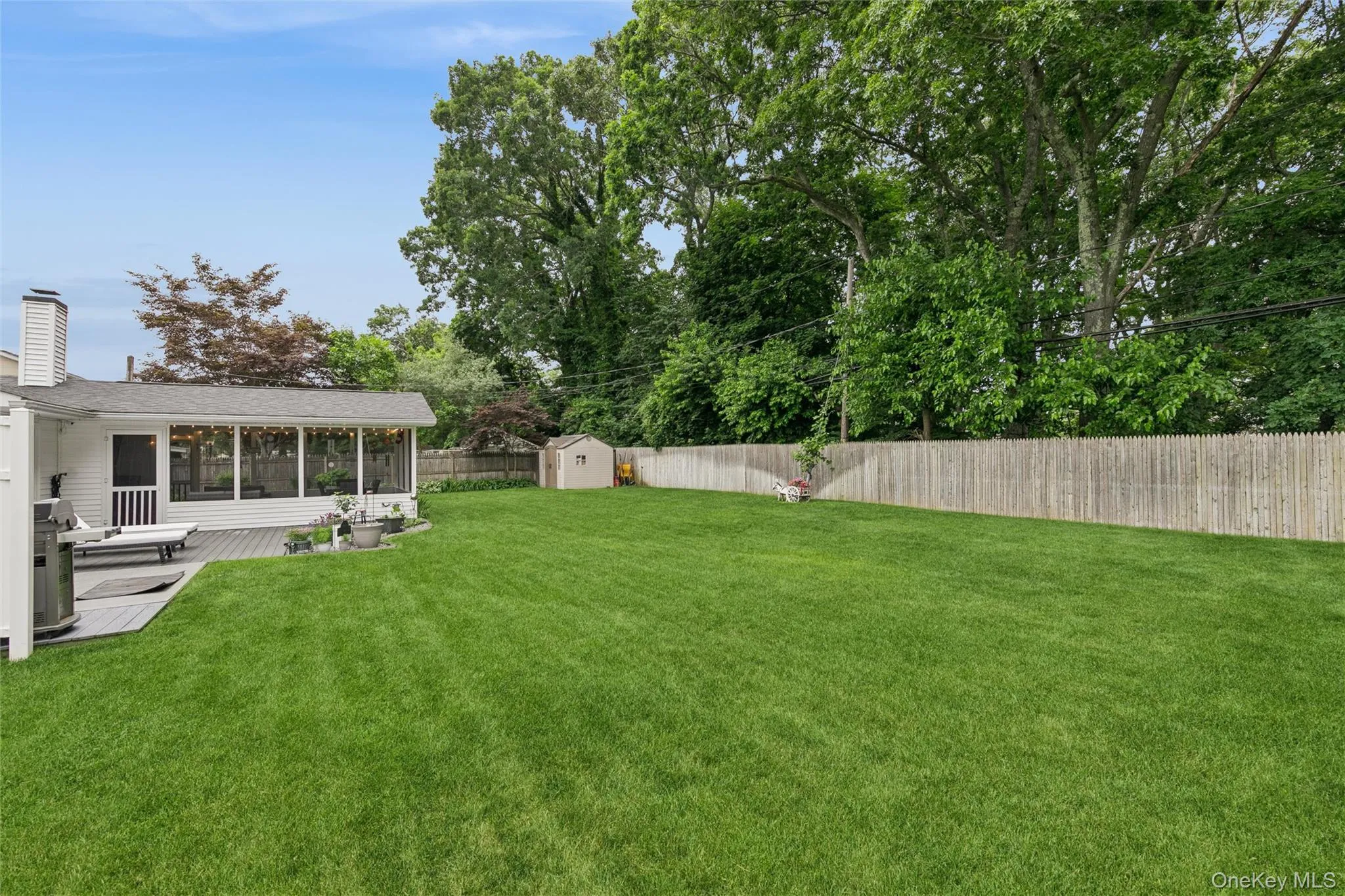 Expansive green lawn with a screened-in porch and an adjacent open deck Expansive green lawn with a screened-in porch and an adjacent open deck