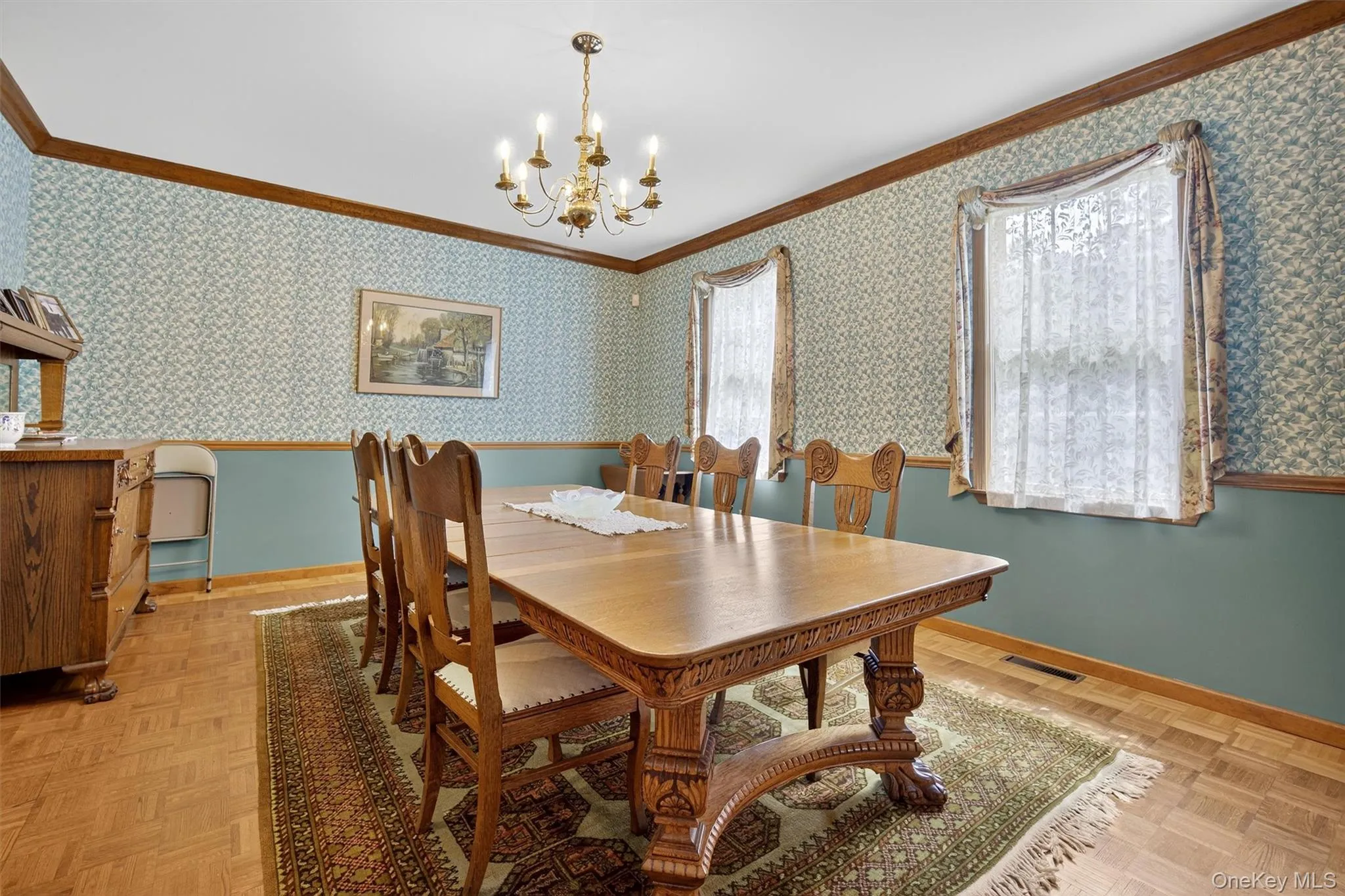 Dining space with crown molding, a chandelier, and wallpapered walls Dining space with crown molding, a chandelier, and wallpapered walls