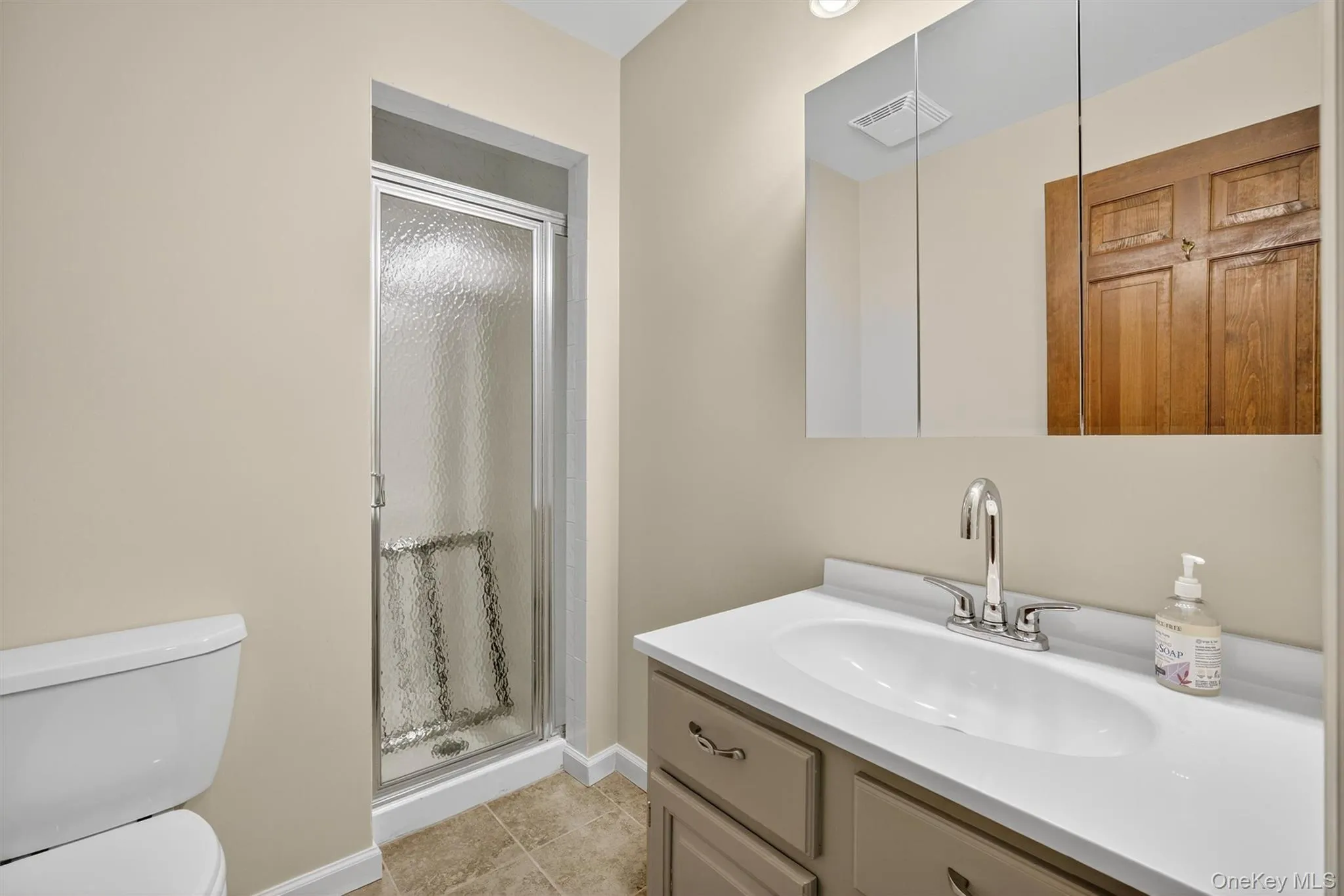 Bathroom with a shower stall, vanity, and tile patterned flooring Bathroom with a shower stall, vanity, and tile patterned flooring