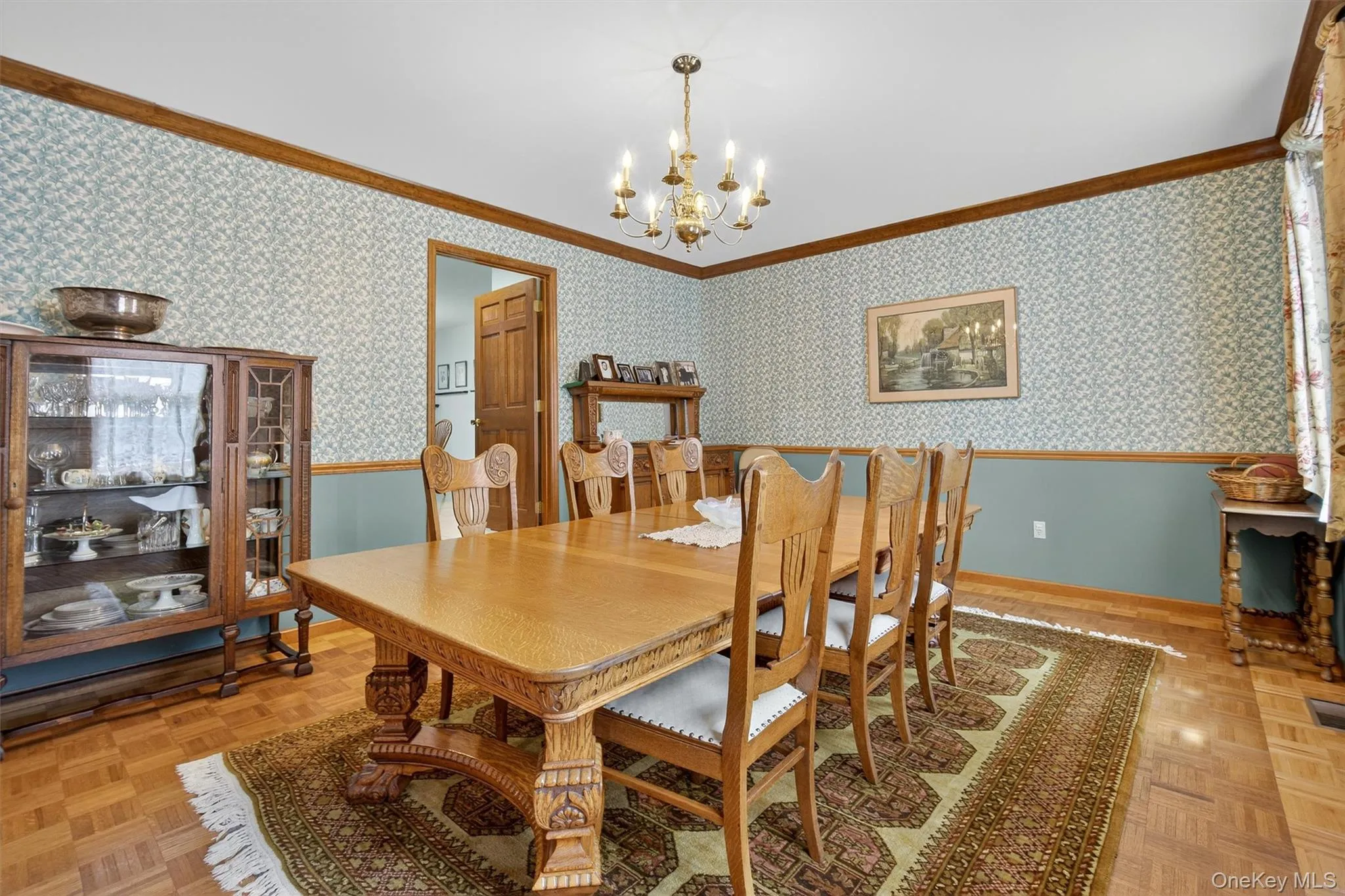 Dining area with ornamental molding, a wainscoted wall, a chandelier, and wallpapered walls Dining area with ornamental molding, a wainscoted wall, a chandelier, and wallpapered walls