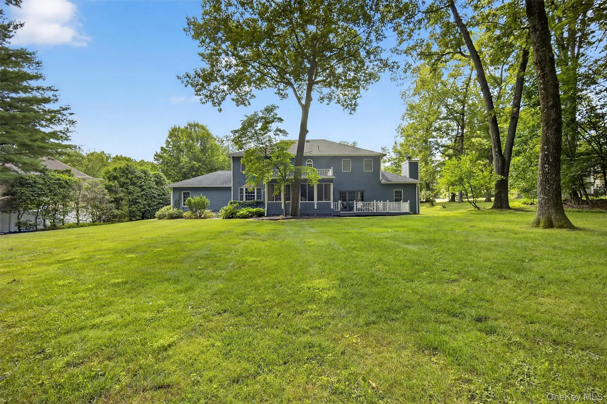 Rear view of property featuring a yard, a chimney, and a deck Rear view of property featuring a yard, a chimney, and a deck
