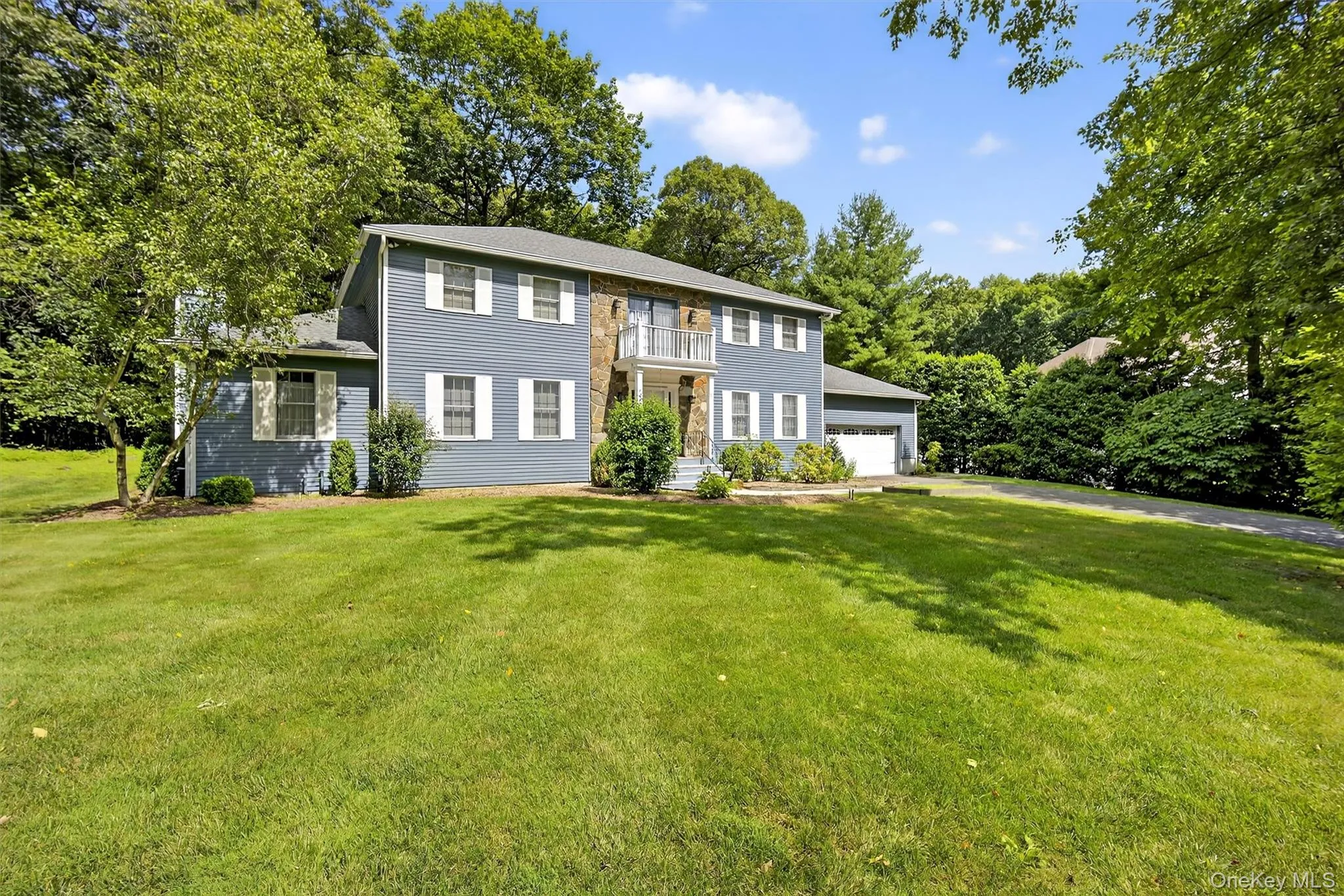 View of front of property with a balcony, a front lawn, and a garage View of front of property with a balcony, a front lawn, and a garage