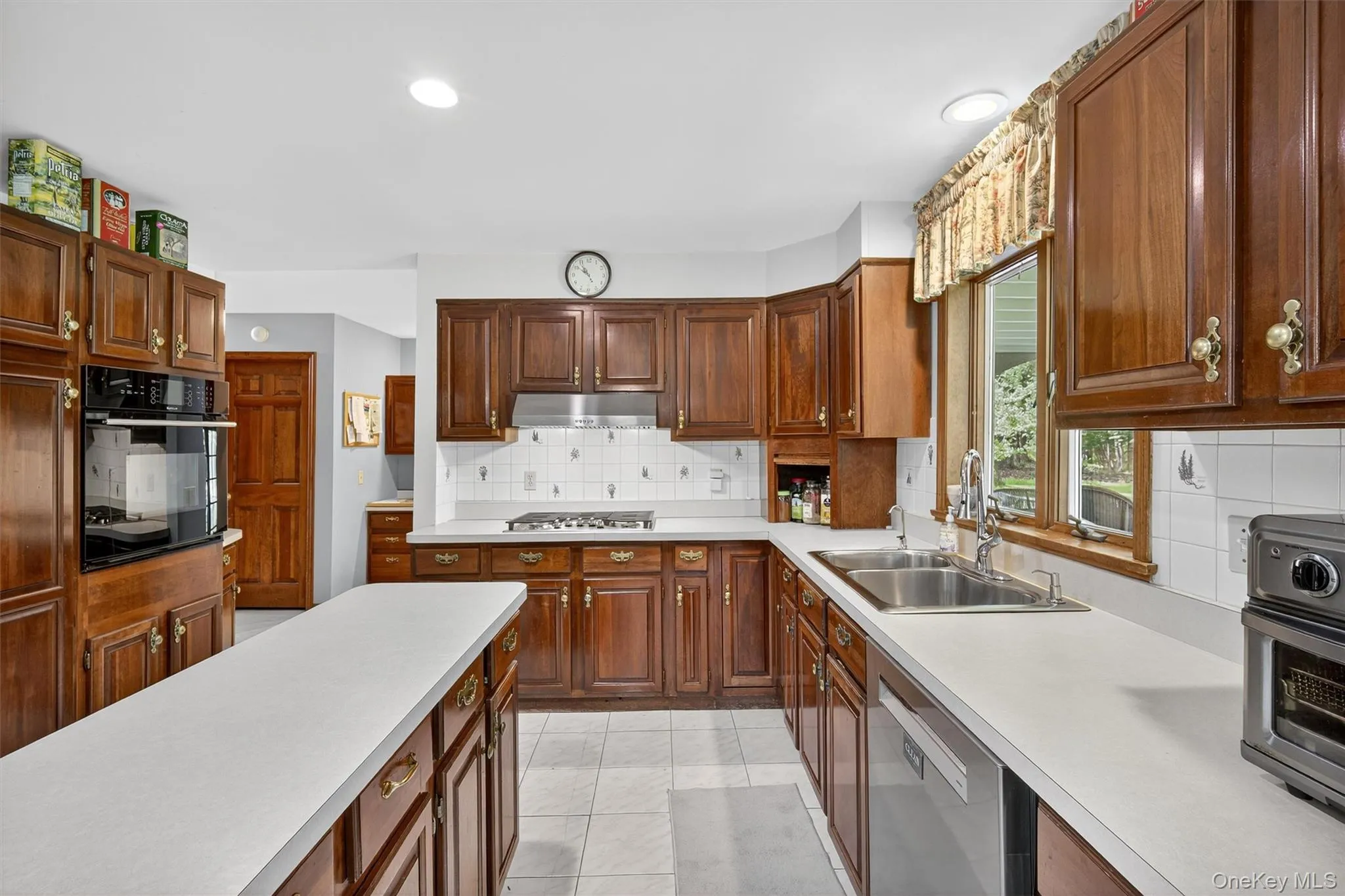 Kitchen featuring appliances with stainless steel finishes, light countertops, under cabinet range hood, decorative backsplash, and recessed lighting Kitchen featuring appliances with stainless steel finishes, light countertops, under cabinet range hood, decorative backsplash, and recessed lighting