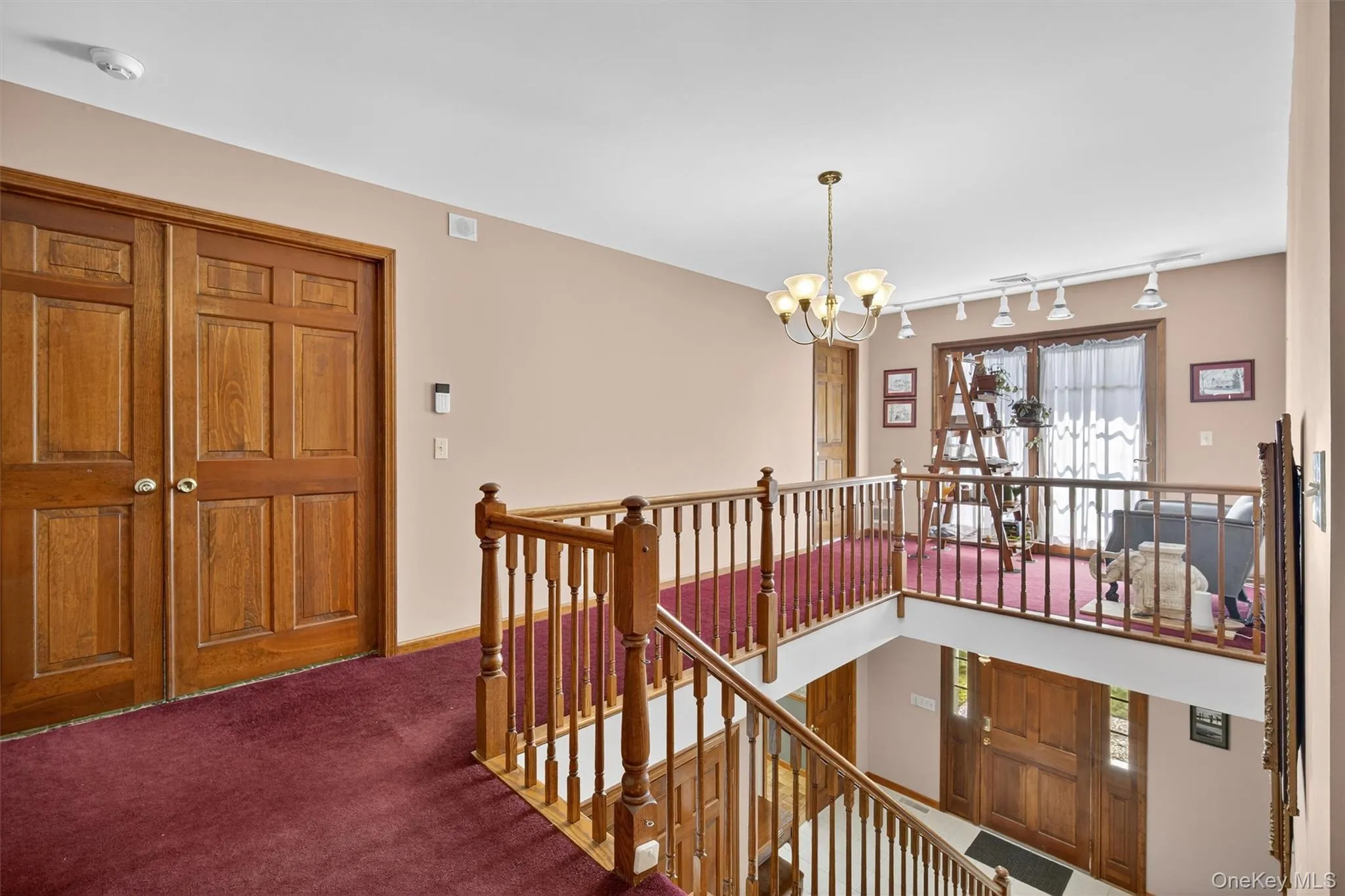 Hallway featuring an upstairs landing, track lighting, carpet, and a chandelier Hallway featuring an upstairs landing, track lighting, carpet, and a chandelier
