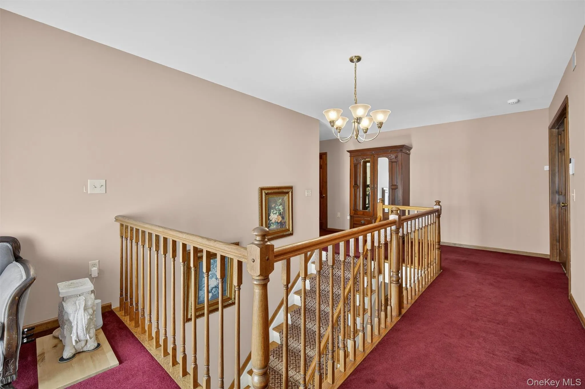 Corridor featuring an upstairs landing, carpet flooring, and a chandelier Corridor featuring an upstairs landing, carpet flooring, and a chandelier